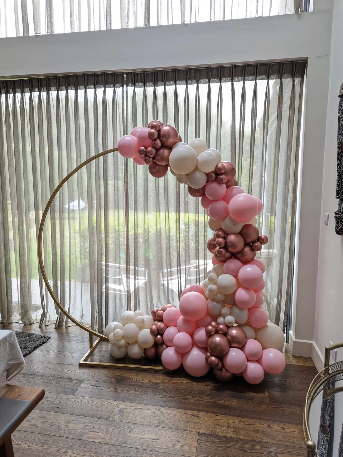 Pink and gold balloon hoop arranged with florals and balloons at an outdoor celebration