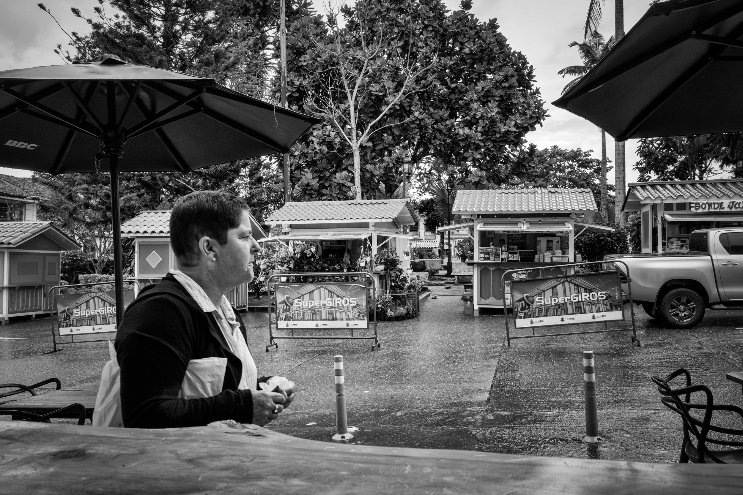 Rainy street scene with people passing by a bar window.