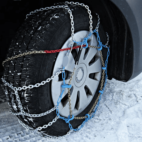 Car tire fitted with snow chains for improved traction on icy roads.