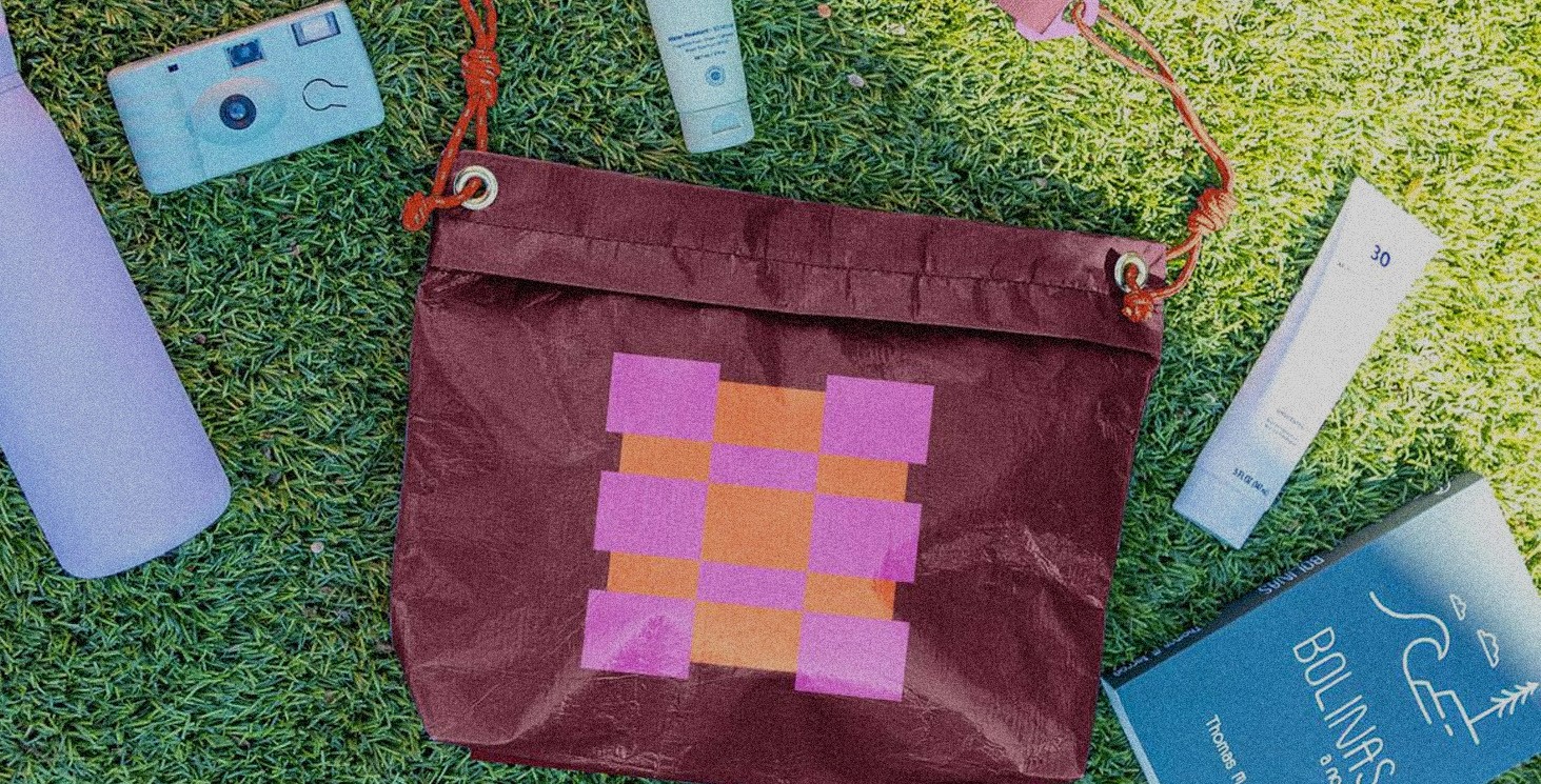 A bag on grass with a few various items placed around the bag as if the bag fall open.