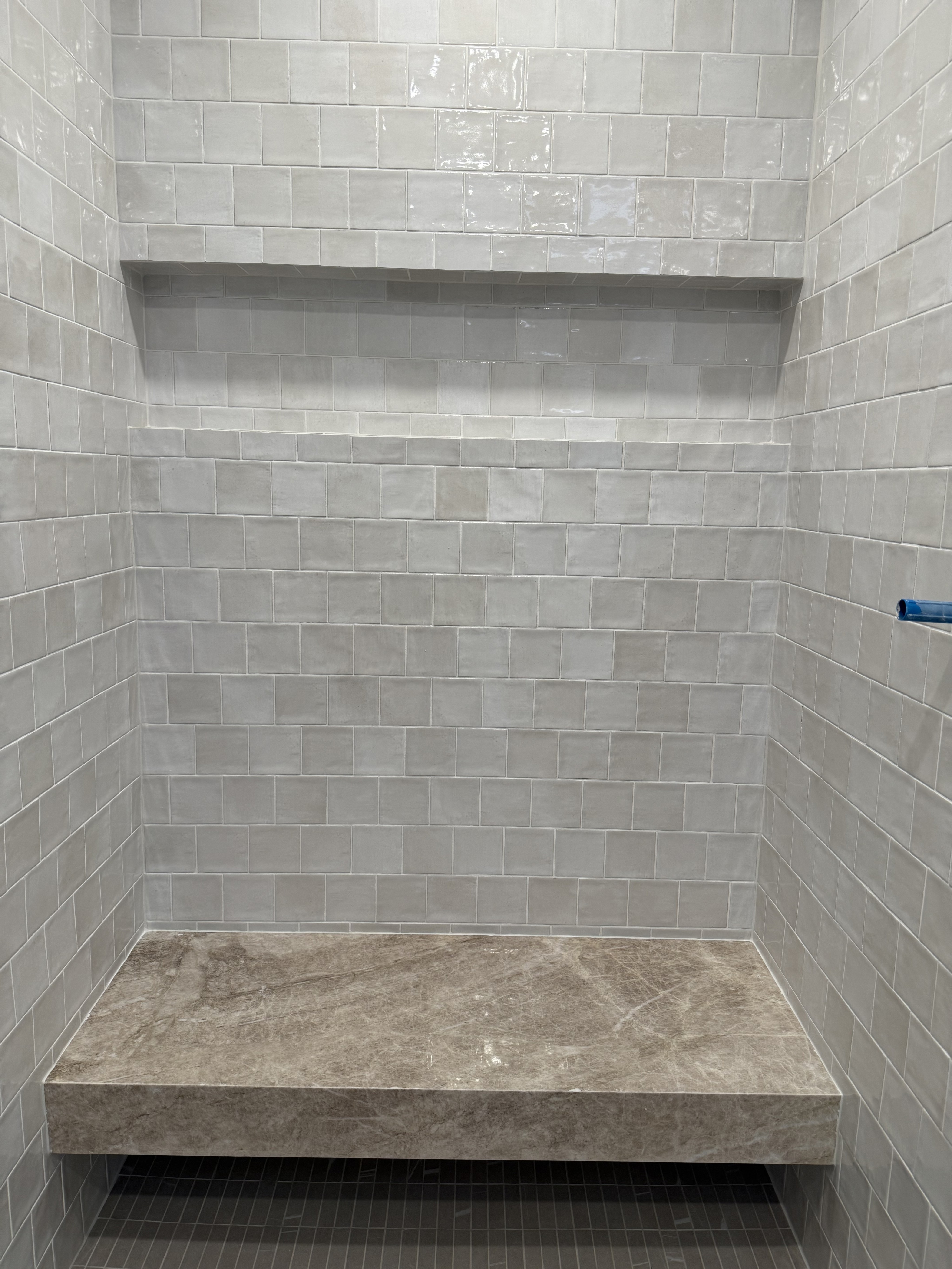 Luxurious bathroom vanity area with a dramatic wall featuring large format natural stone tiles in varying earthy tones and complex veining, serving as a striking backsplash above a double sink vanity.