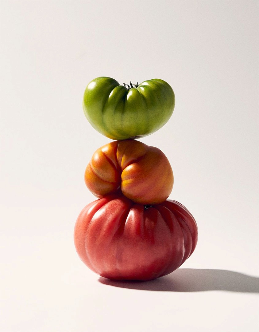 stacked of green, orange and red tomatoes