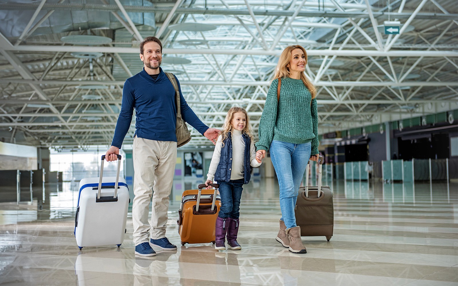 Family with luggage walking through Gatwick Airport terminal.