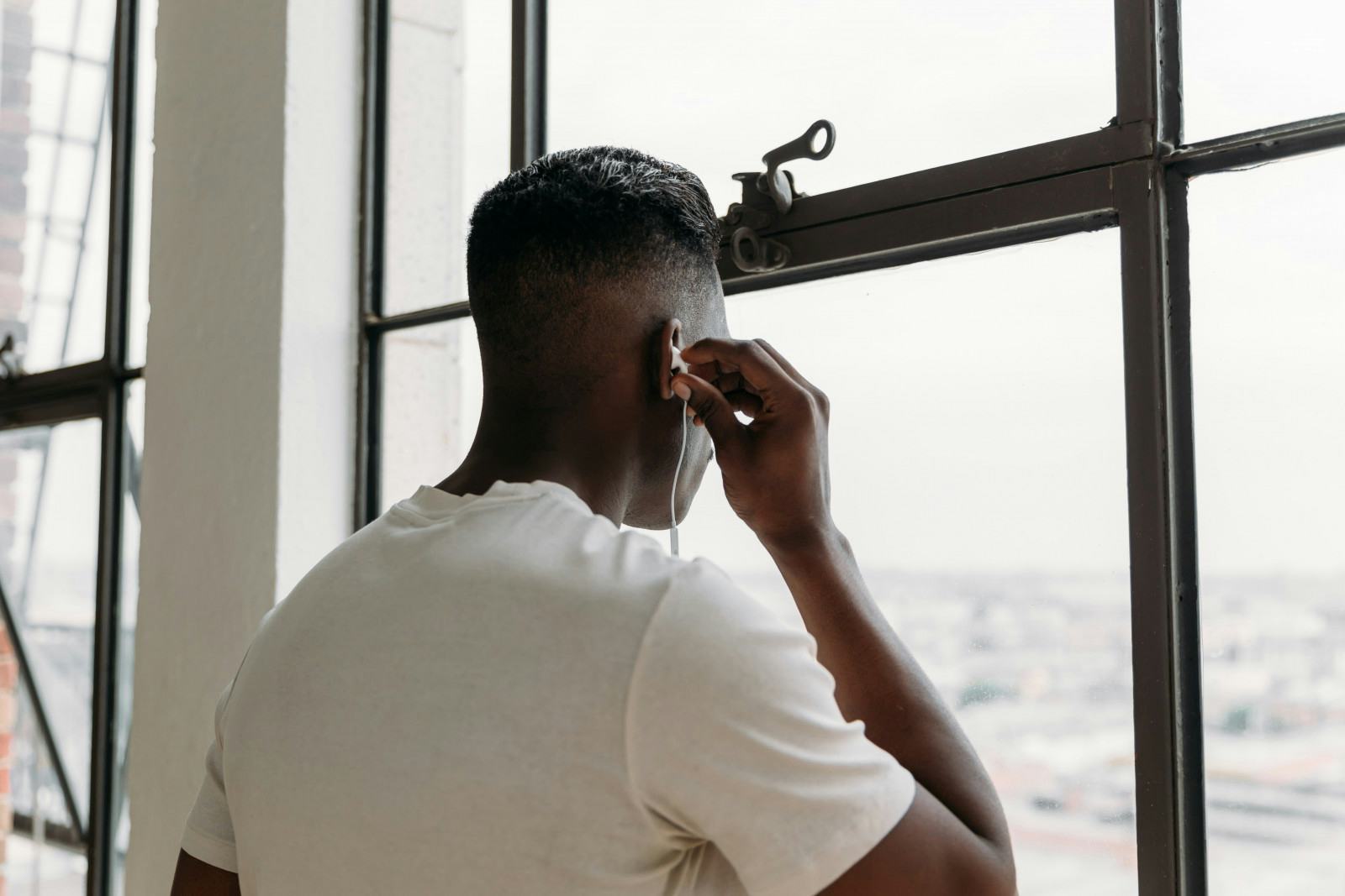 A man stands by a window, engaged in a phone conversation, with natural light illuminating the scene