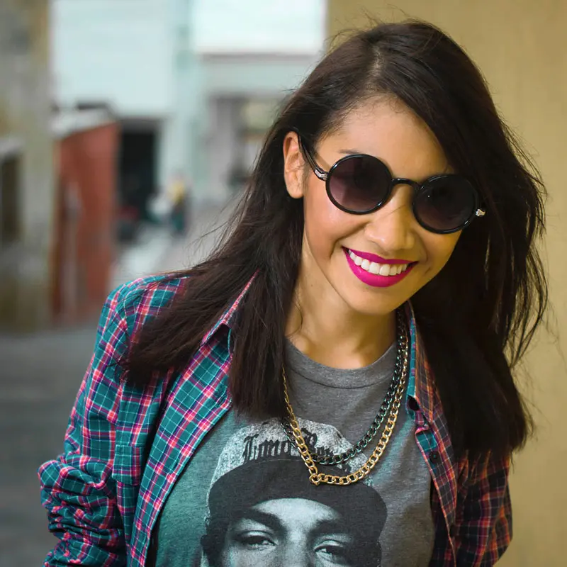 Fotografía de una mujer joven de piel morena y cabello largo negro, con expresión intelectual y entorno de estudio, representando el perfil de una estudiante de filosofía y letras.