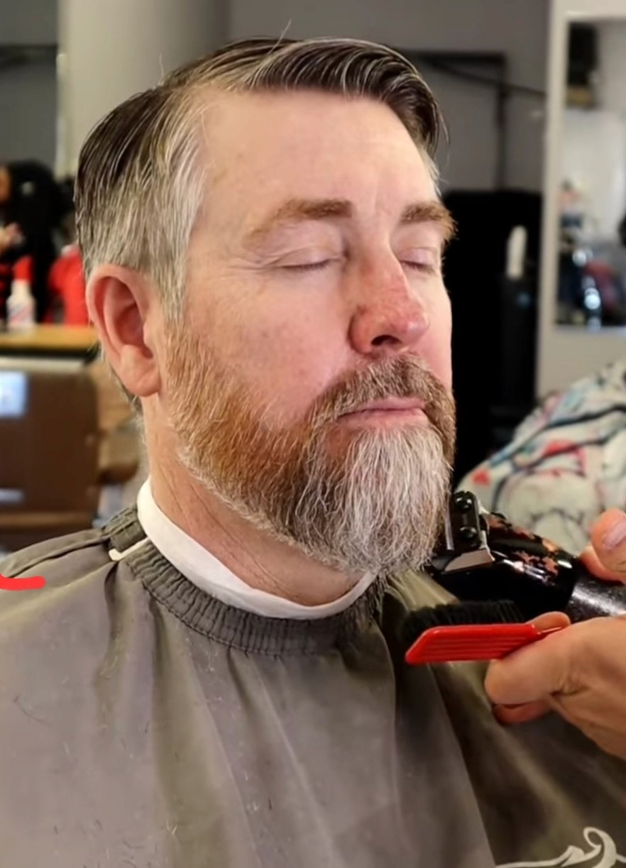 Man in barber chair getting beard trim