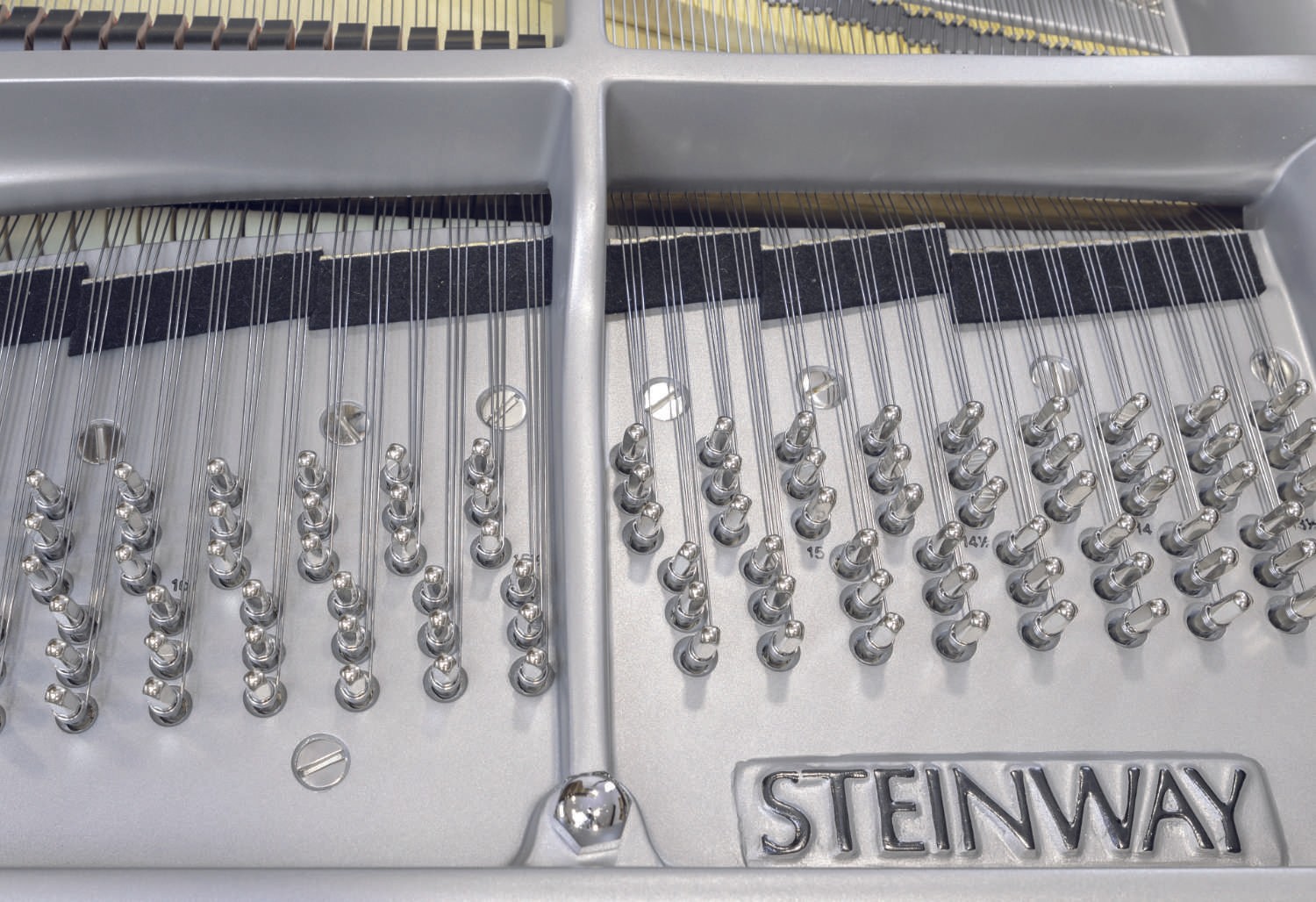 A macro shot of the gray iron frame inside a restored Steinway & Sons grand piano, showcasing its strong and refined design.
