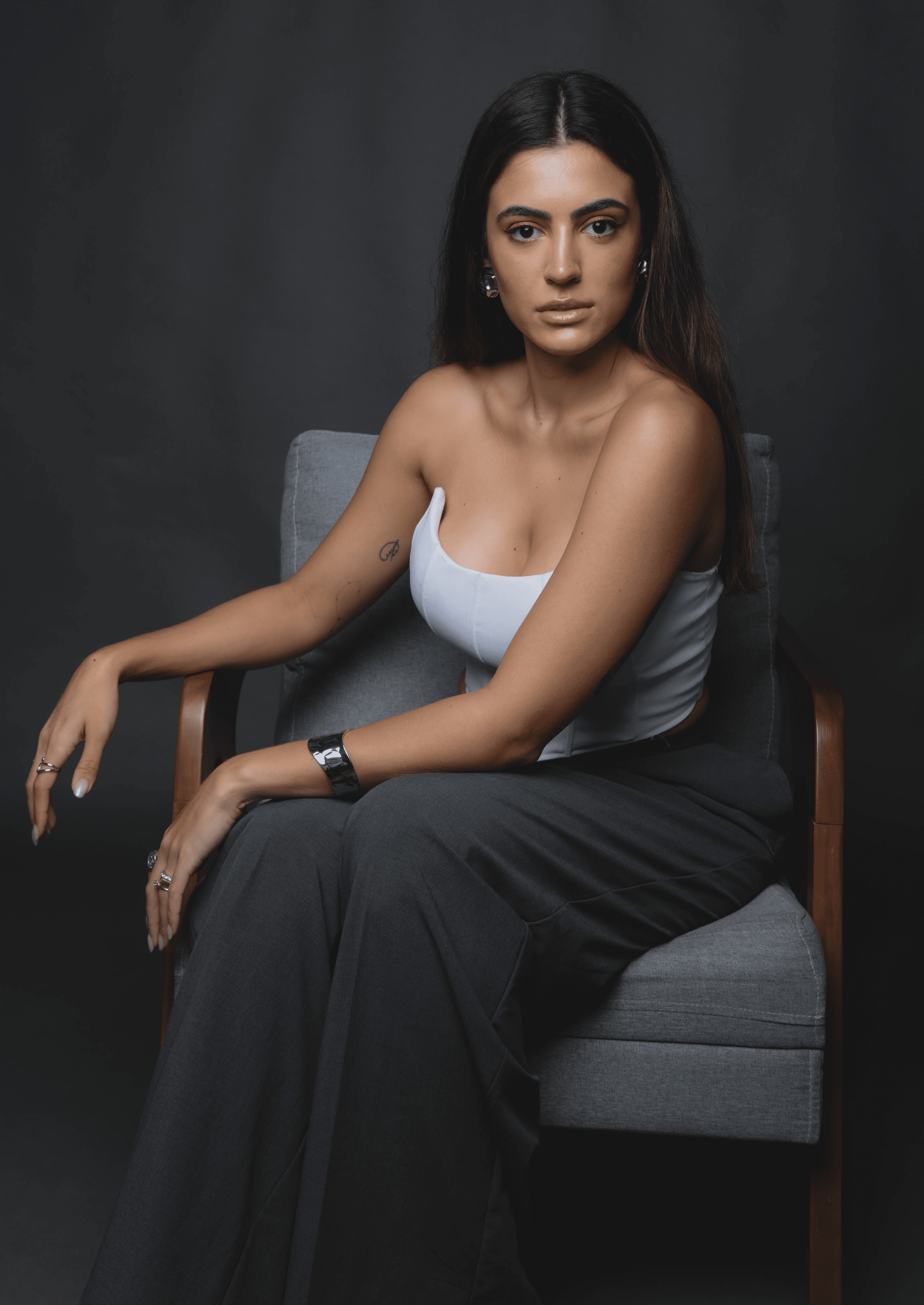 Smiling female therapist with short gray hair, wearing a brown top and a purple shawl, surrounded by a cozy background.