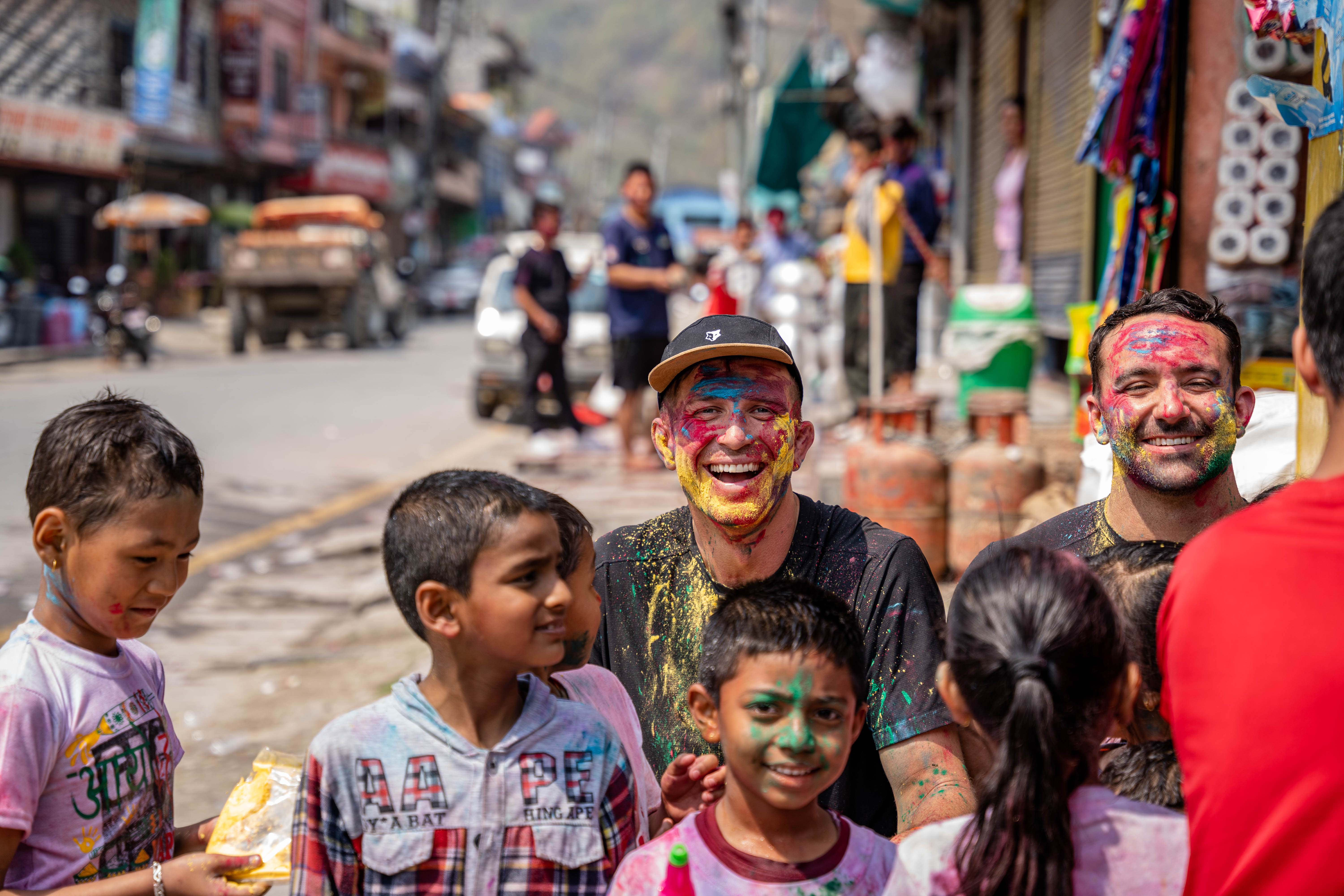 Ed Jackson covered in coloured powder celebrating Holi with children in a Nepali street