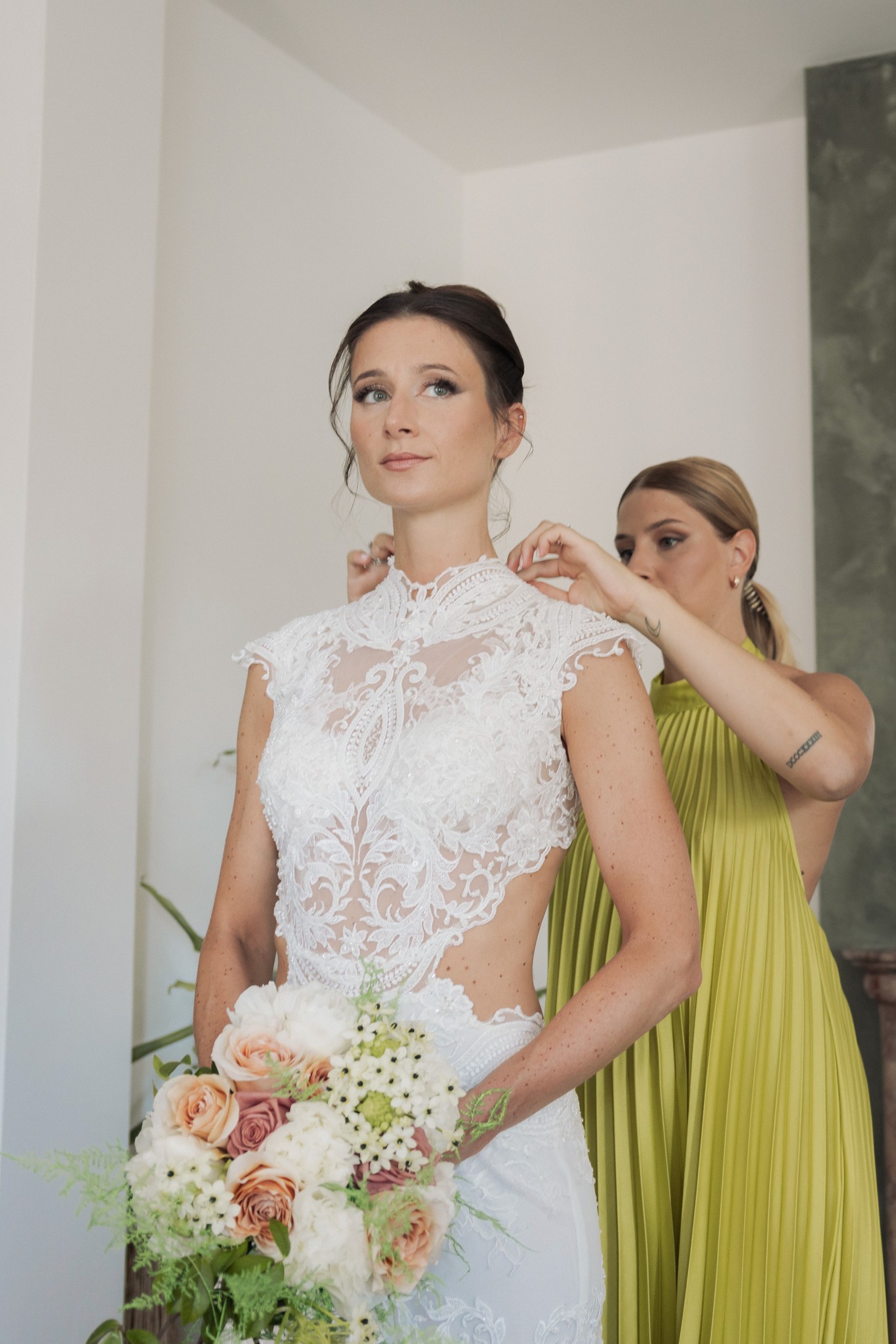 Sposa in abito di pizzo riceve gli ultimi ritocchi dall'amica damigella prima della cerimonia al Rocca di Soragna