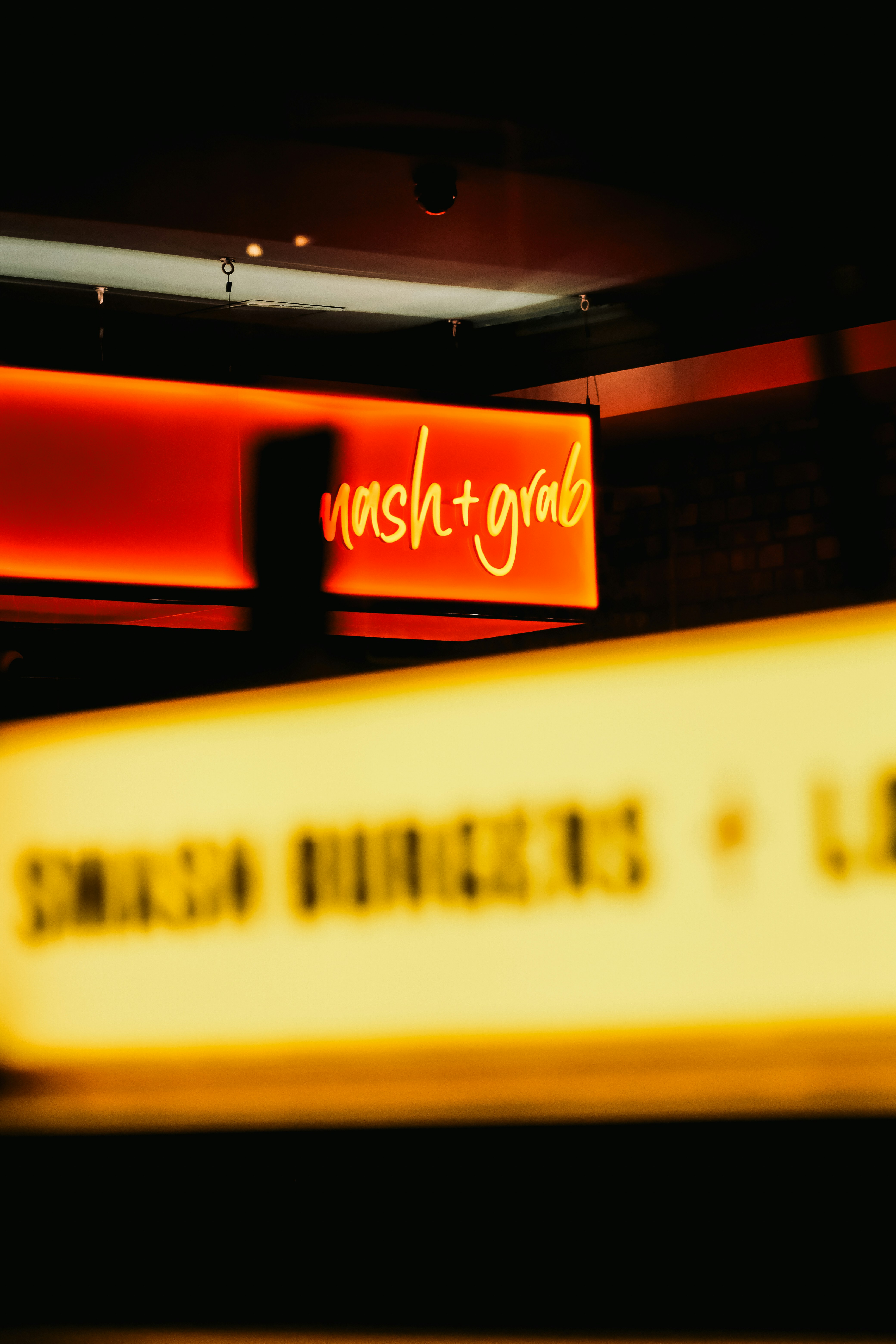 Bright neon sign says "nash + grab"