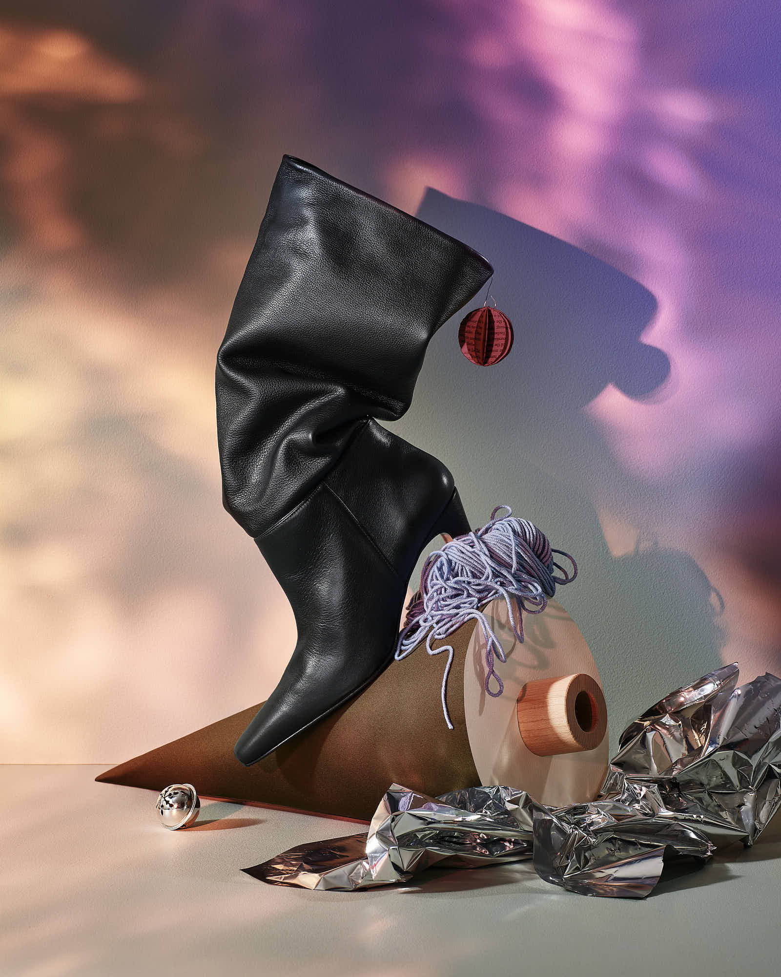 Elegant black leather boot with artistic decor and colorful background, modern fashion photography.