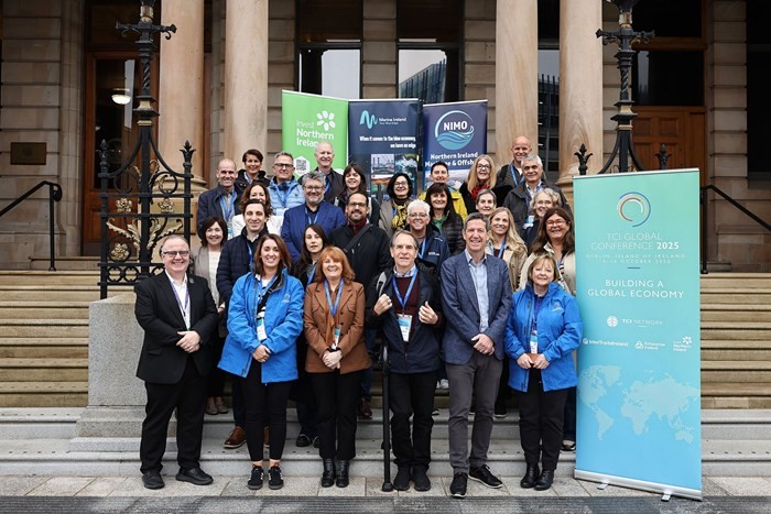 A group of people poses on steps, holding signs and banners, in front of a building.