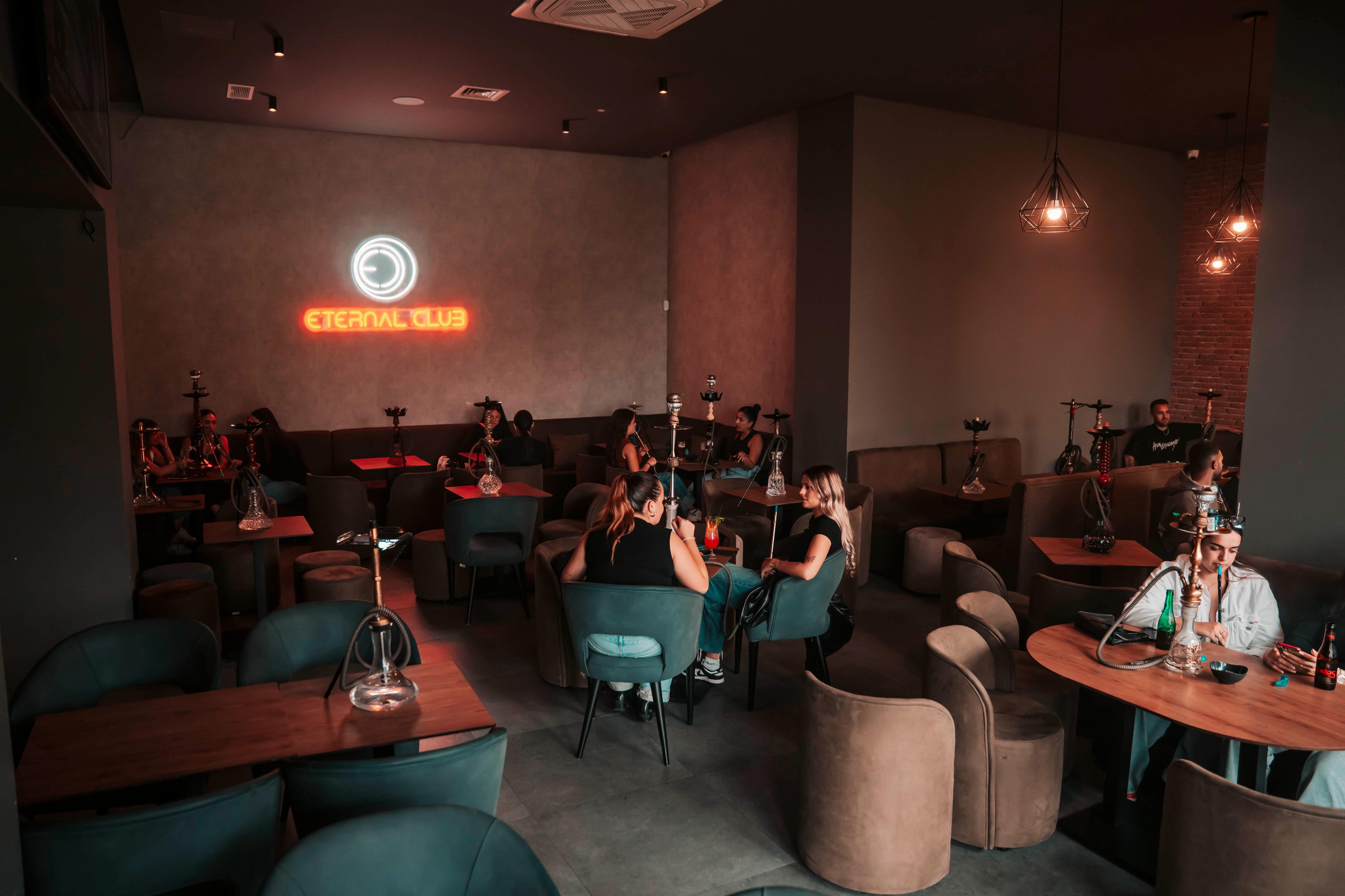 Shisha lounge moderno con logo neón y ambiente relajado.