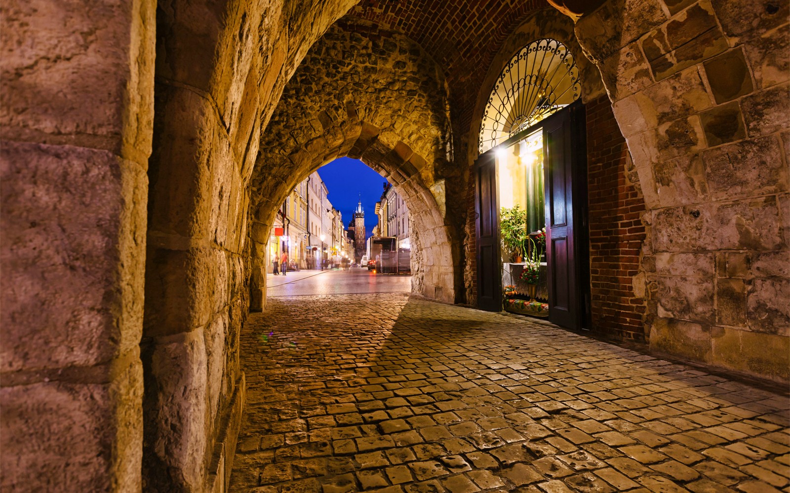 Stadsgezicht van Krakau door een stenen boog 's nachts.
