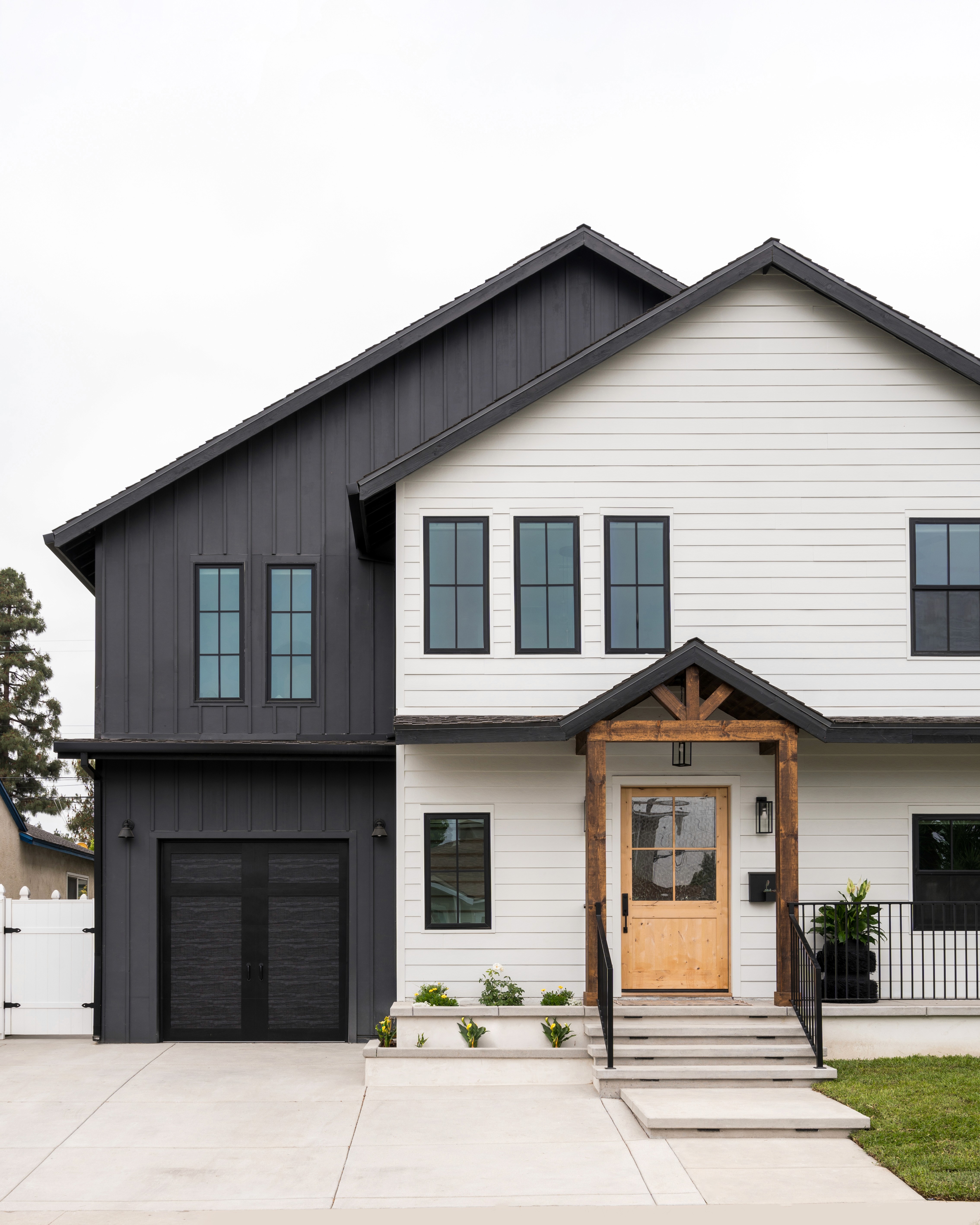 A two-story home with white siding and warm wood accents by Jubilee Interiors located in Westlake Village, CA