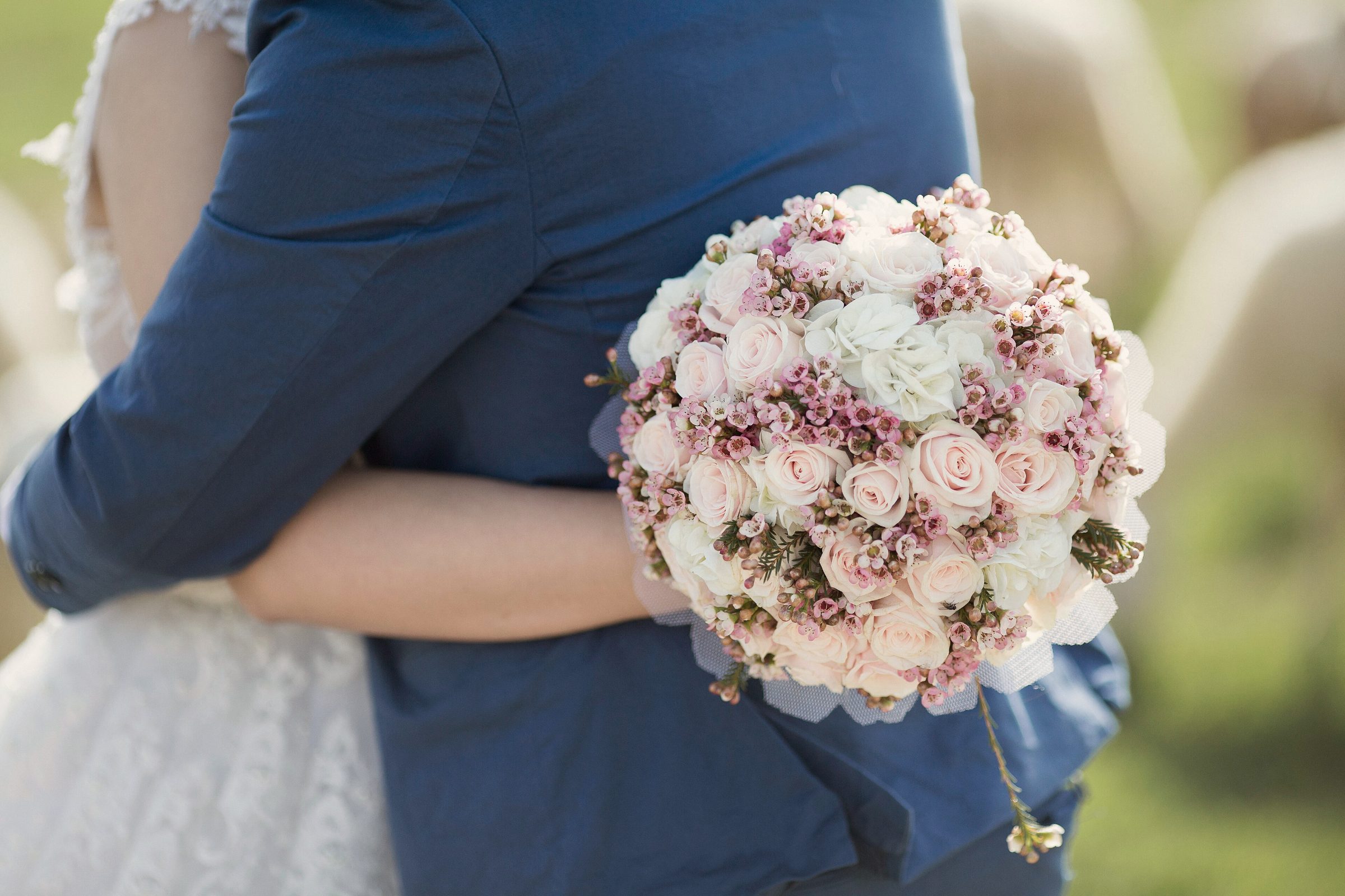 An embrace with a round bouquet of pink roses