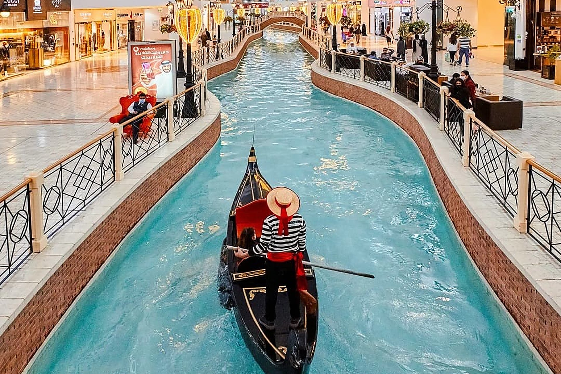 Un gondolier au chapeau de paille qui conduit sa gondole sur le canal intérieur du Villaggio Mall, à Doha