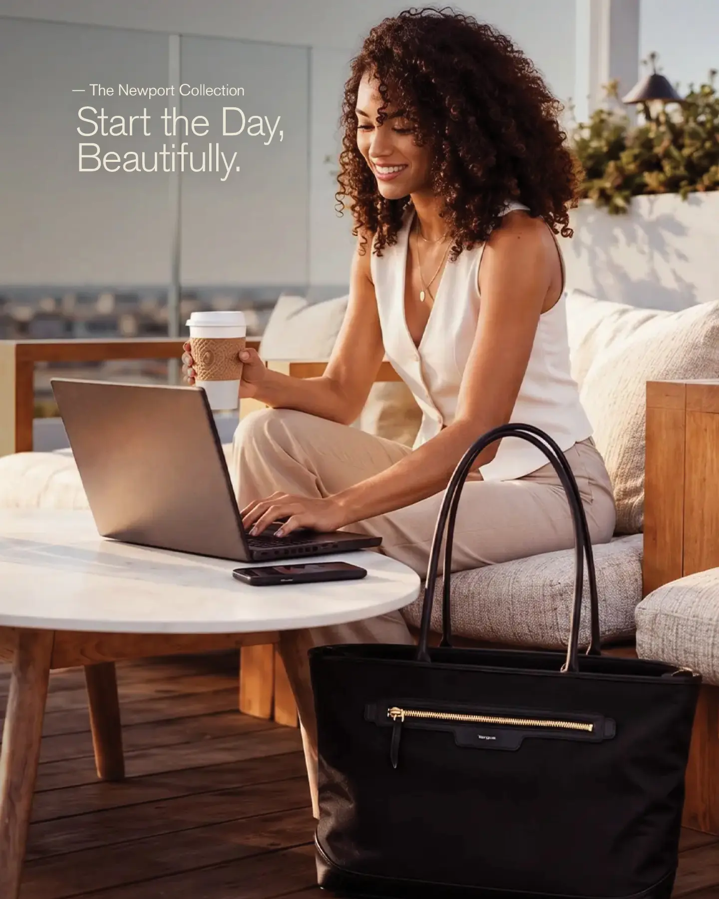Woman working on a laptop with a black Newport tote beside her.
