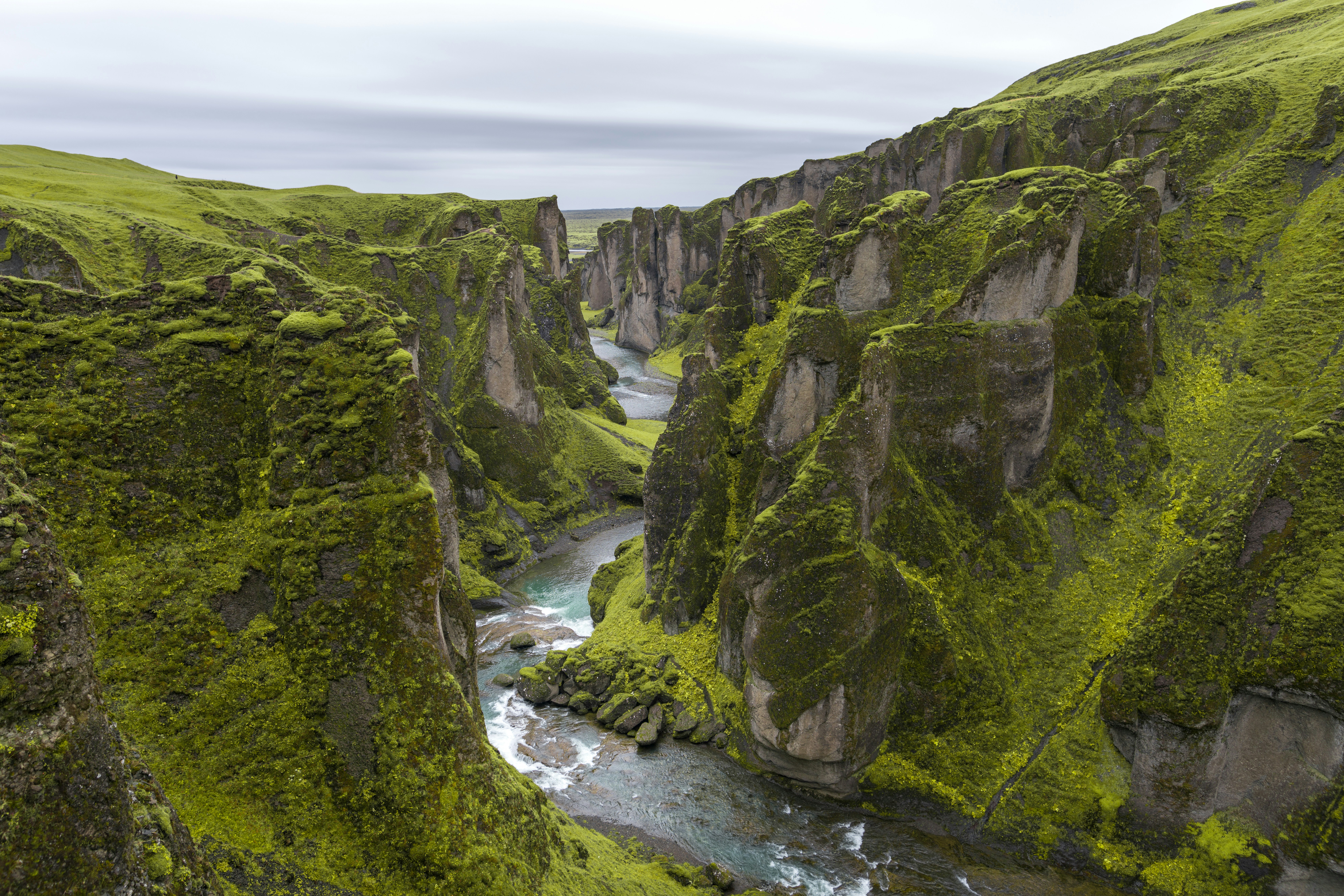 Steep green cliffs and winding river at Fjaðrárgljúfur Canyon in South Iceland.