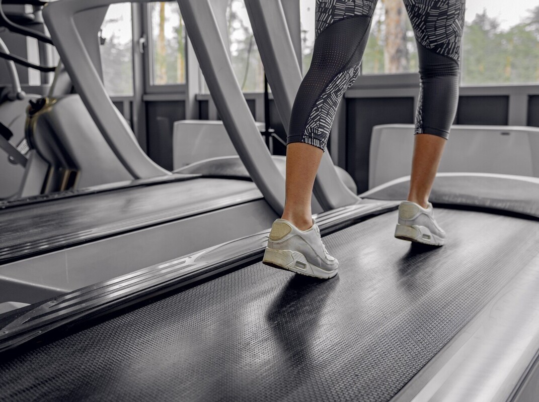 legs of a woman at the gym doing a gentle warmup incline treadmill workout for weight loss