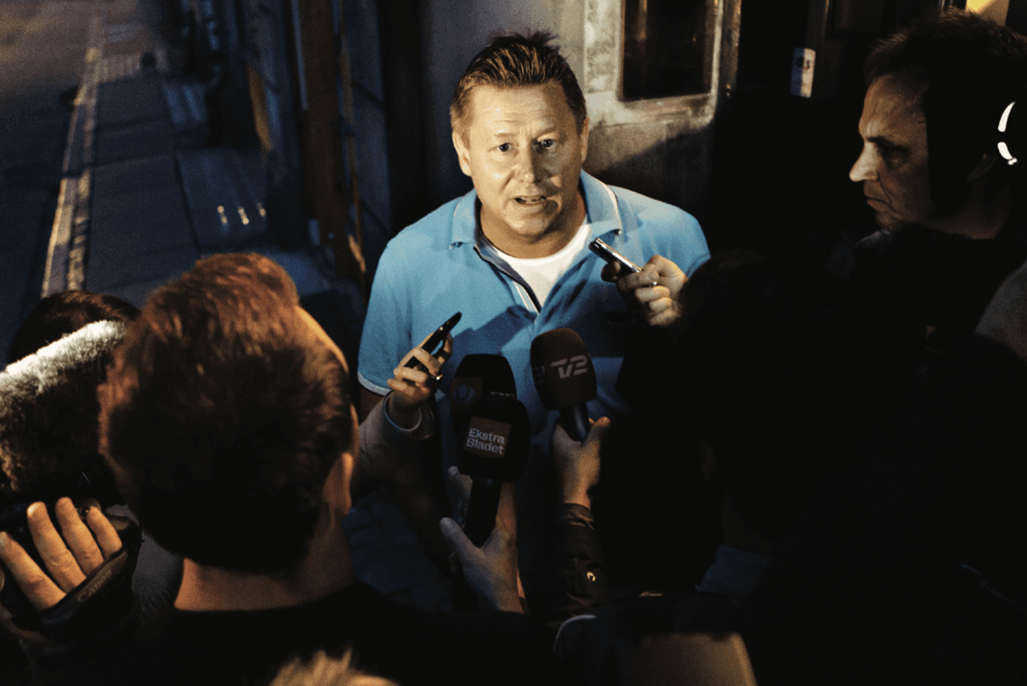 Focused woman working on a laptop in a cozy, dimly lit café with a tea glass on the table.