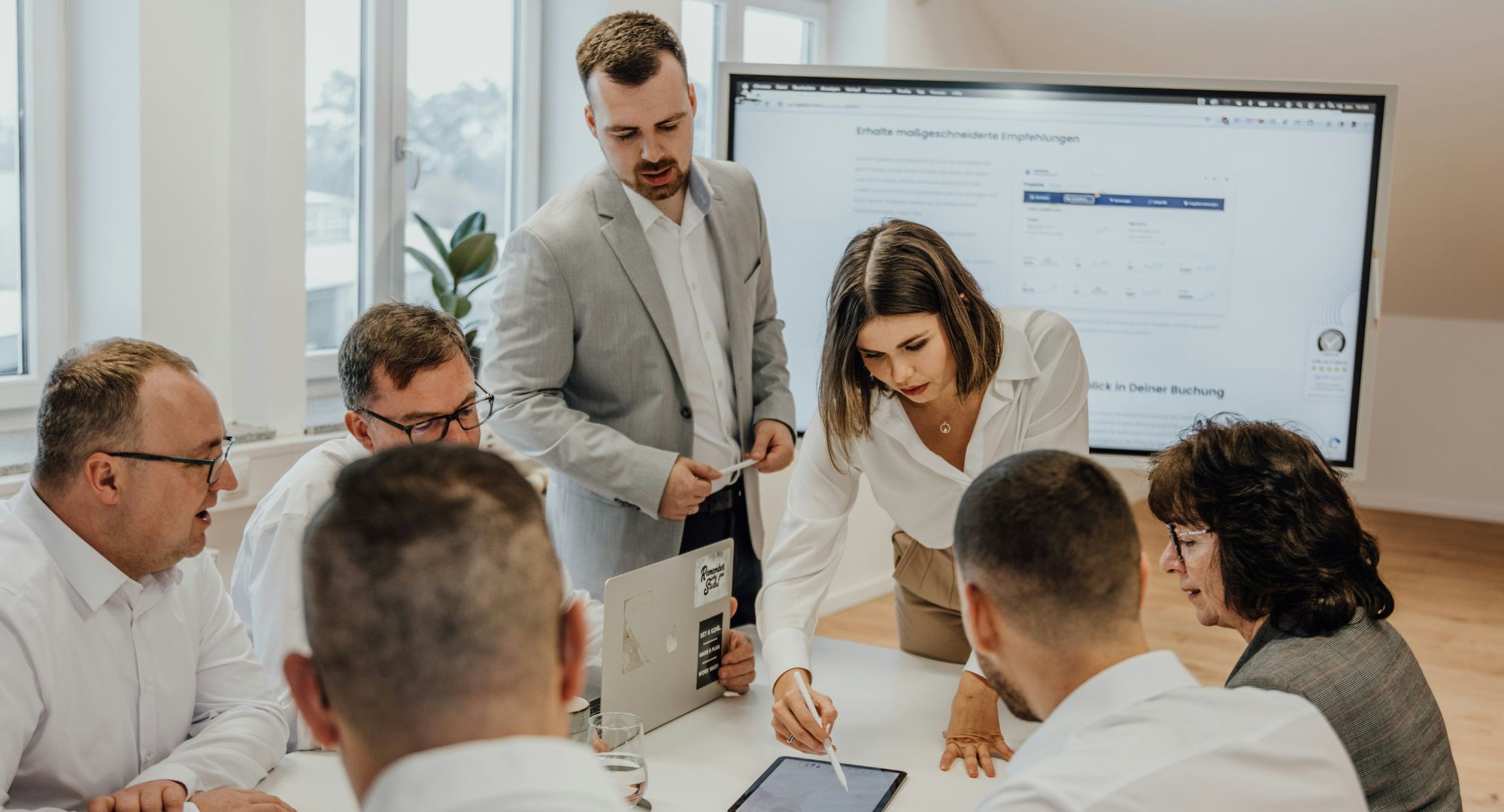 sala de reuniões com pessoas analisando informações em um tablet em cima mesa
