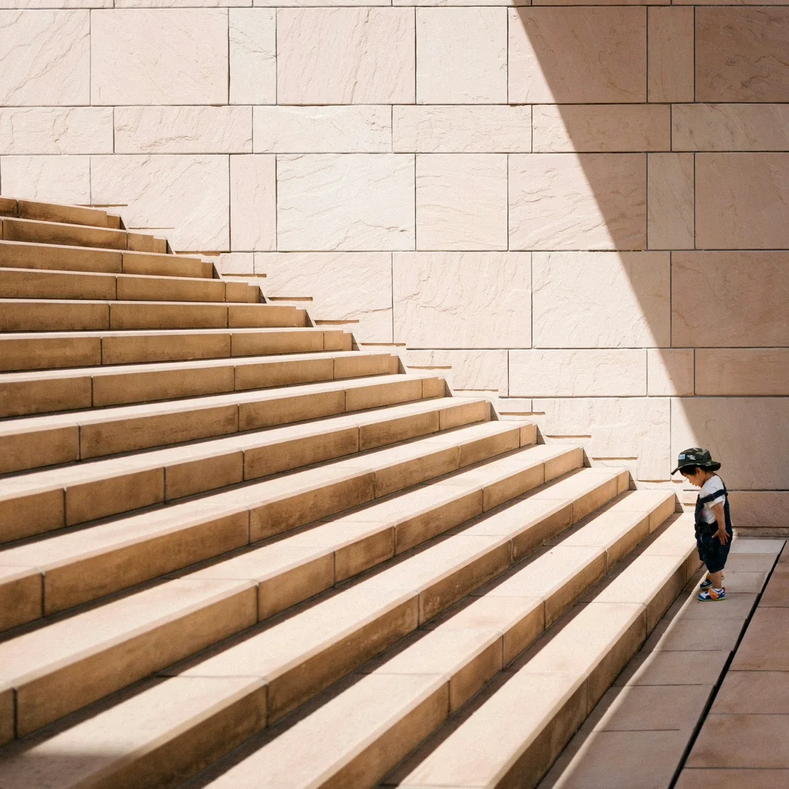 Child standing at the bottom of large stairs symbolizing challenges and growth, representing the first steps toward support through online therapy in New York.