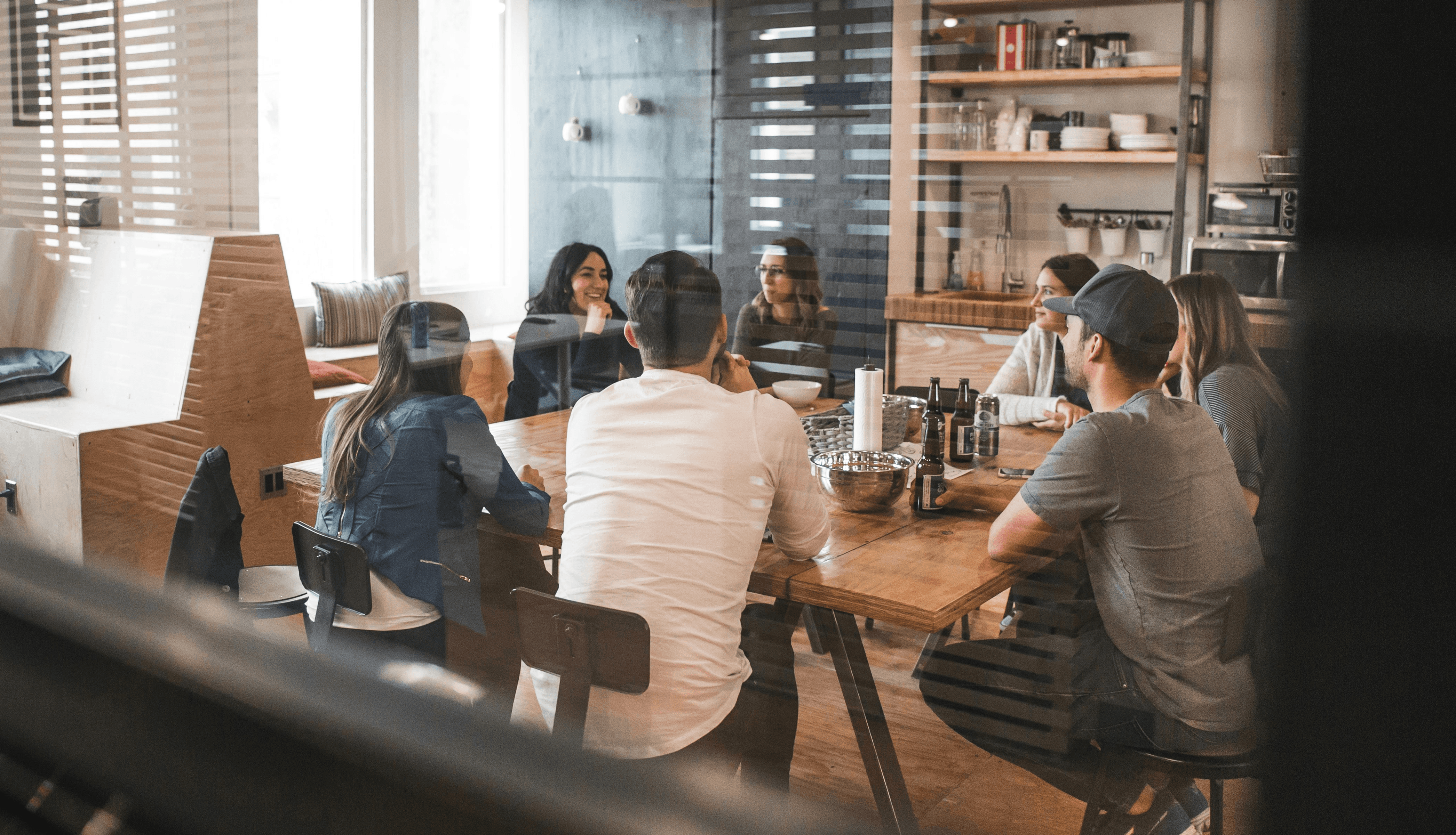 A team of colleagues meeting in a workplace lunch room setting