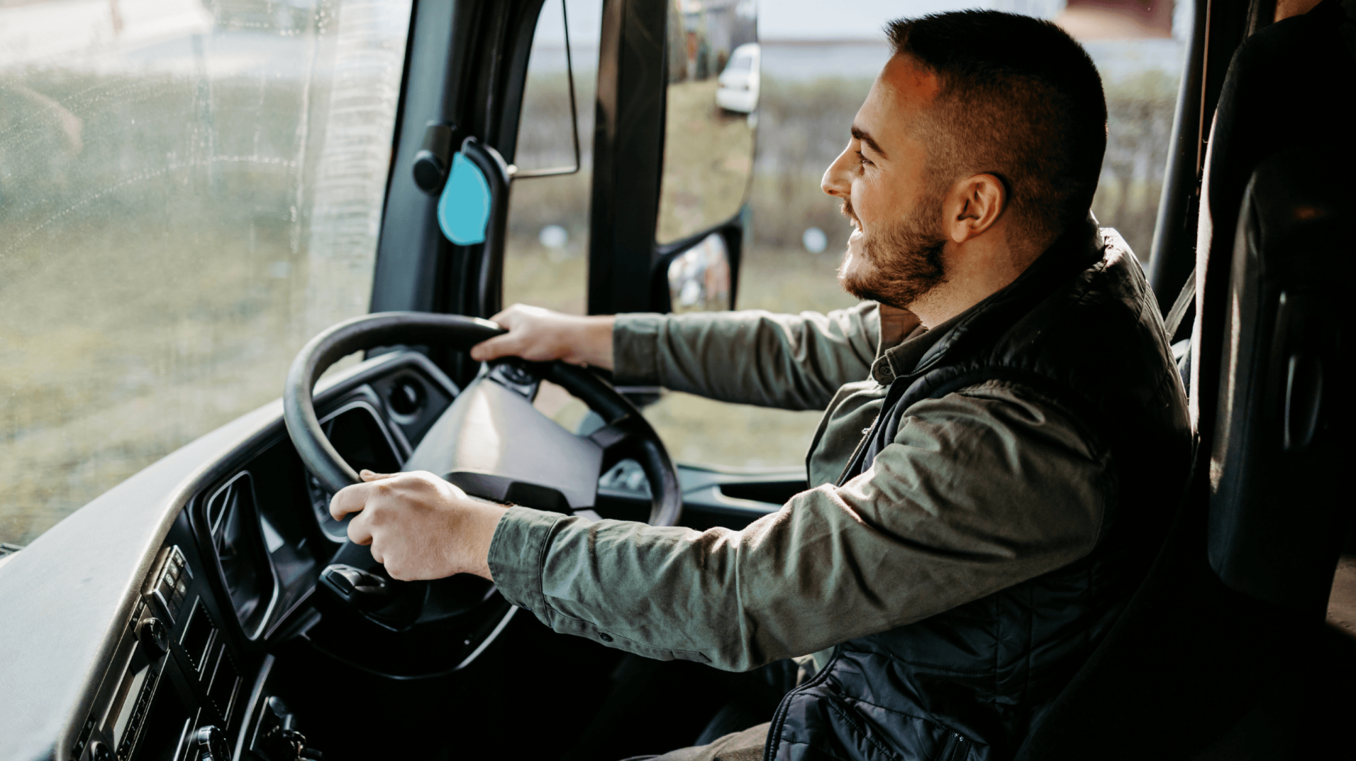 A man driving a truck and smiling.