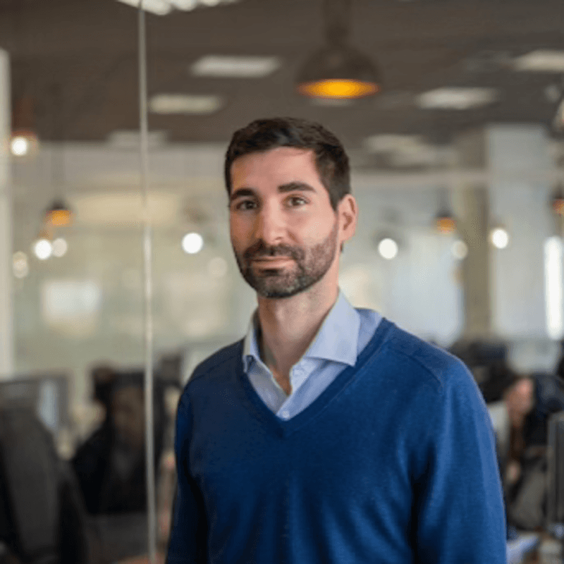 Uomo con maglione blu che sorride in un ambiente d'ufficio