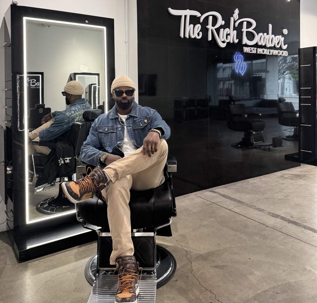 Courtney Palmore, also known as Barber.CLP, sitting confidently in a barber chair at The Rich Barber in West Hollywood, showcasing his expertise in professional grooming and luxury barbering services.