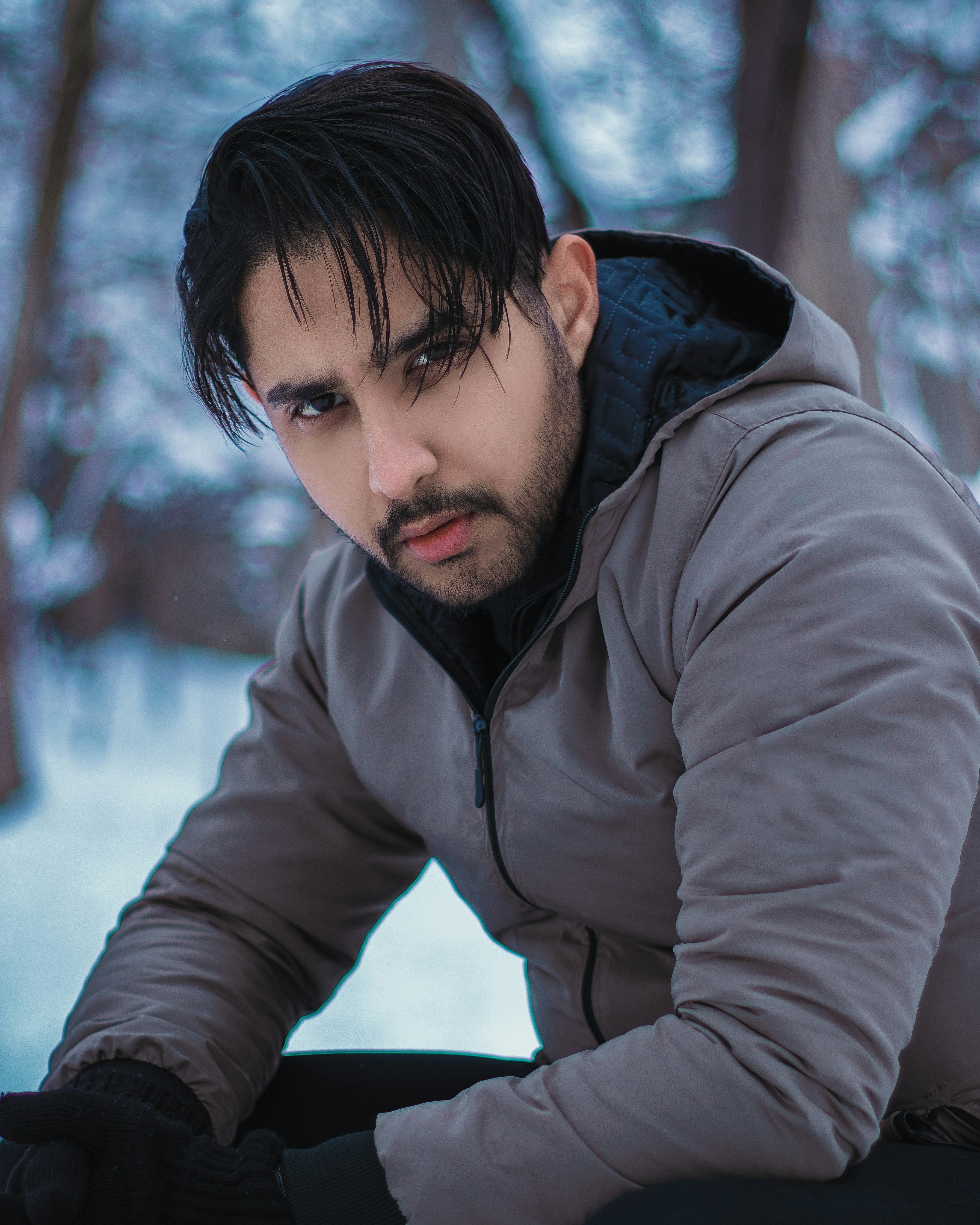 a man with black hair sitting in the snow