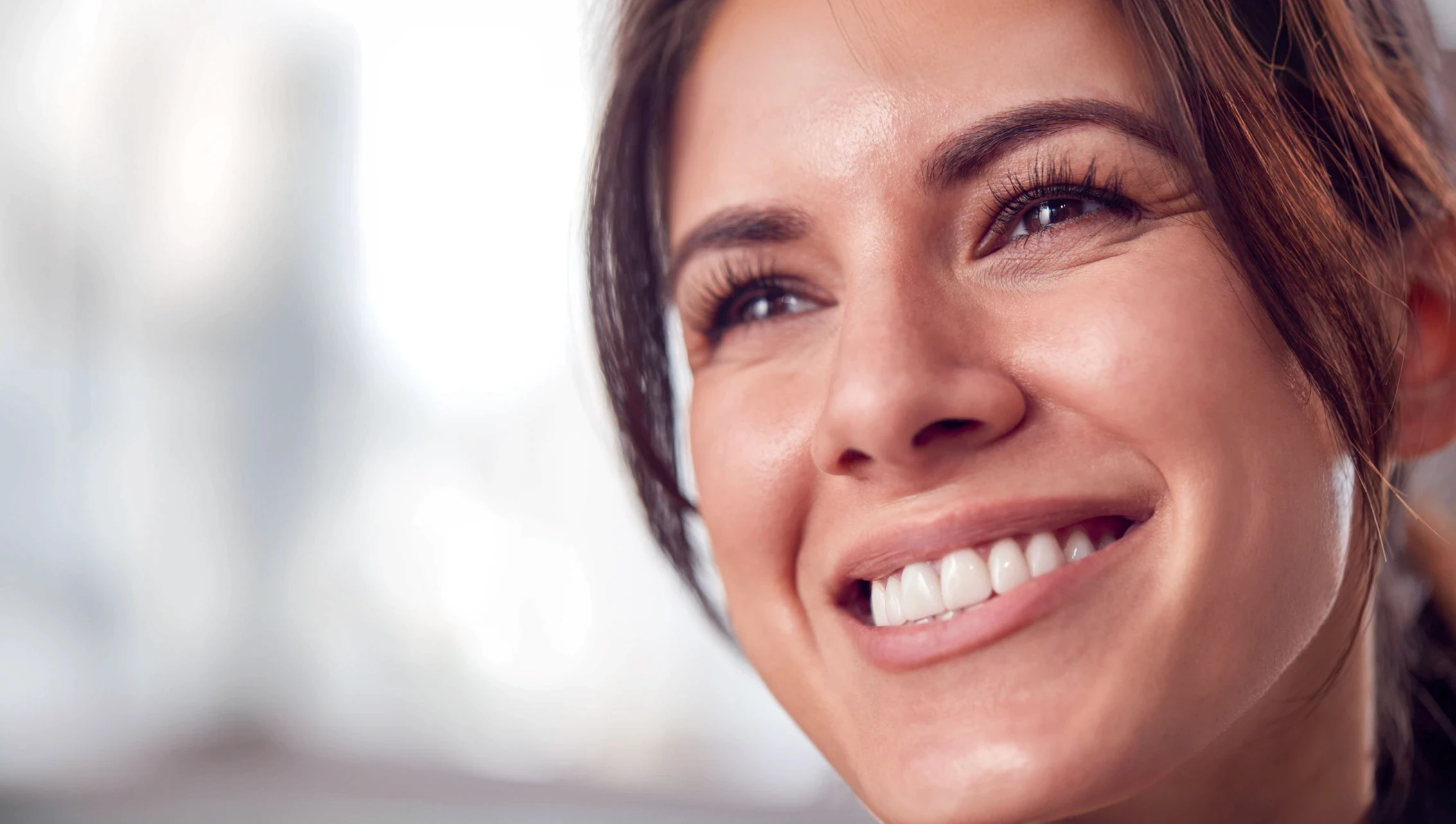 Kobieta z uśmiechem prezentująca efekty bondingu na swoich zębach.