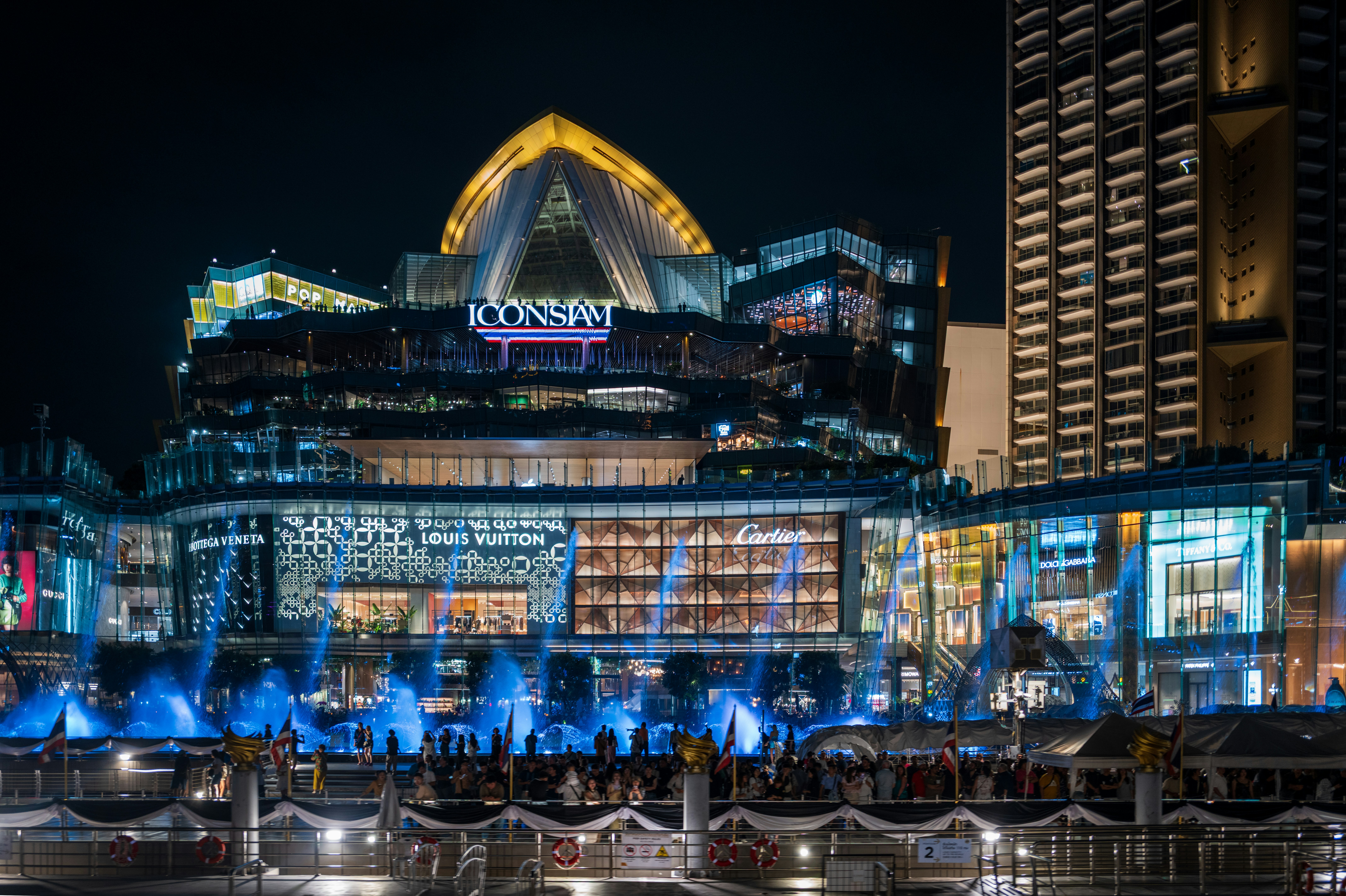 Modern illuminated buildings at night with water features.
