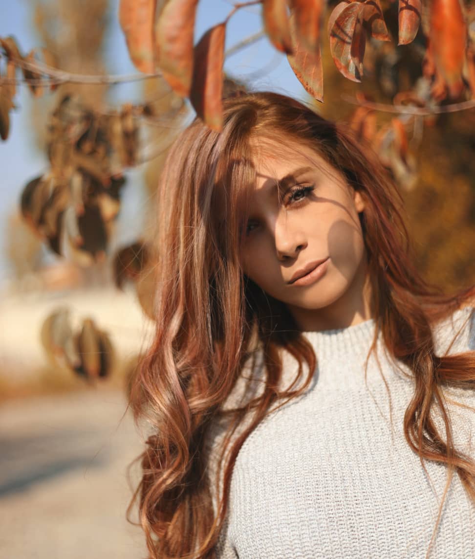 Beautiful girl standing near tree foliage