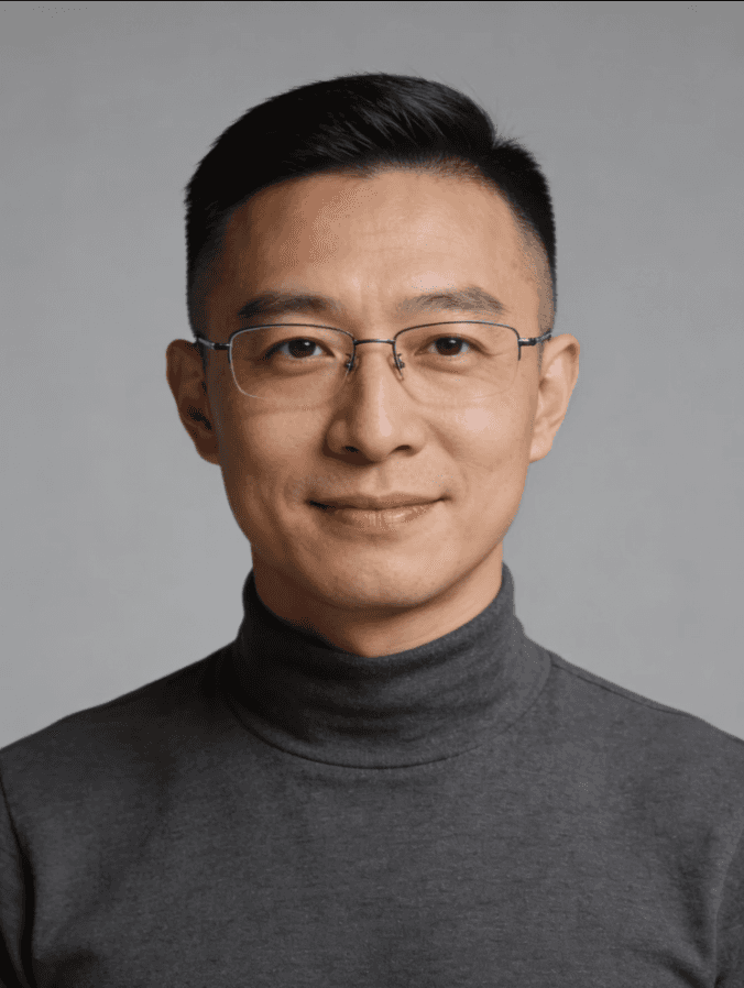 Lower face portrait of a smiling man in a grey collared shirt against a gray background.
