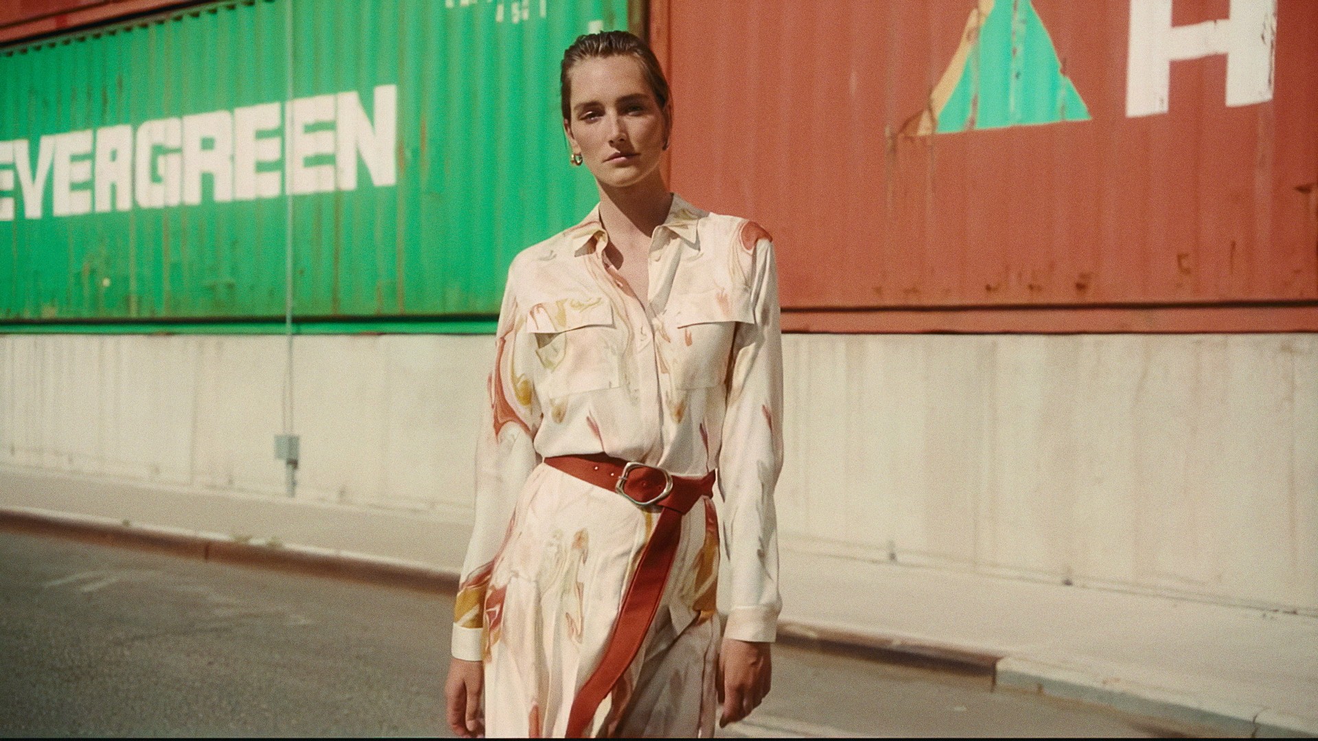 A woman in a cream printed shirt and skirt in front of an Evergreen shipping container, Lafayette 148 New York