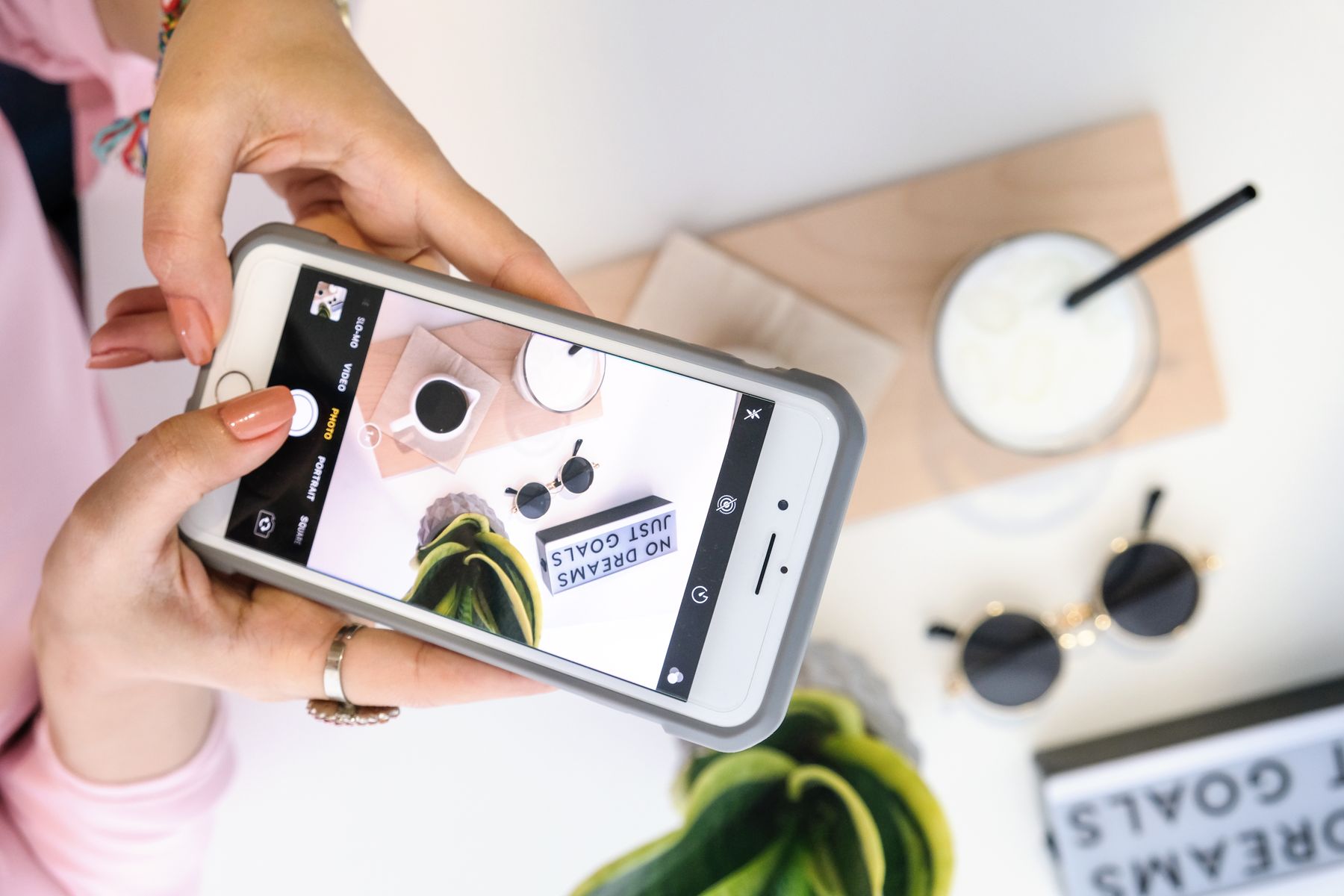 A woman photographing a styled product setup with a smartphone