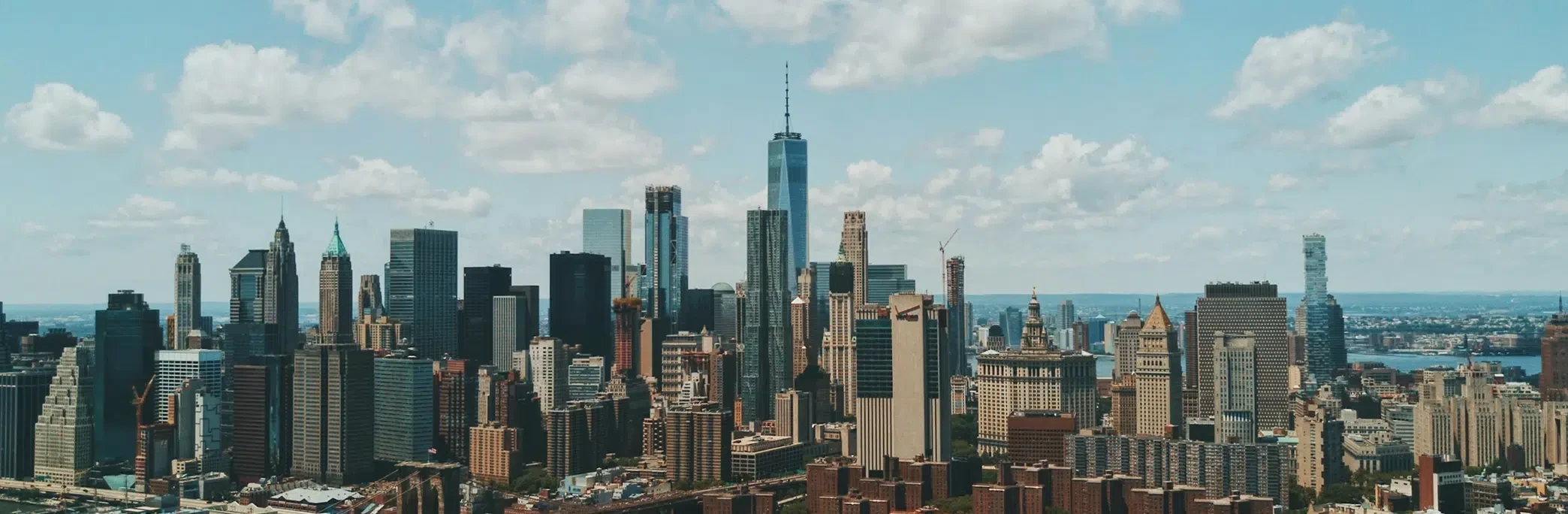 Panoramic aerial view of the New York City skyline with numerous skyscrapers and the iconic One World Trade Center.