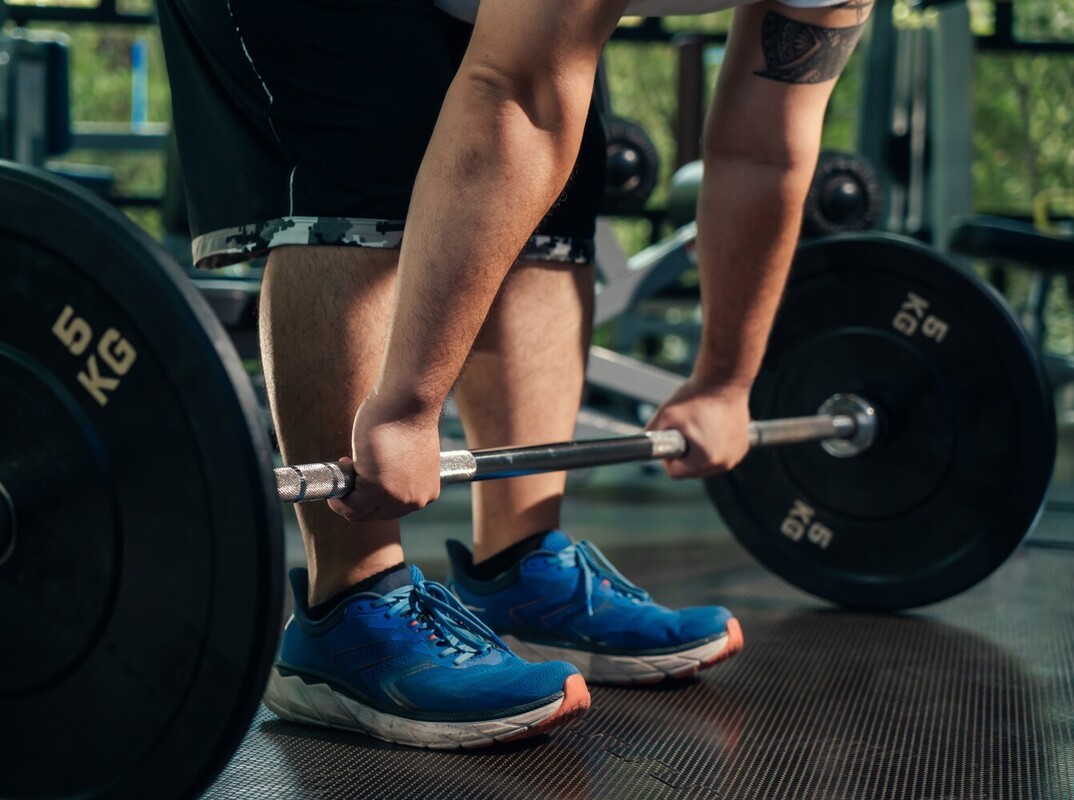 overweight man performing deadlifts with a barbell as part of his weight loss gym workout