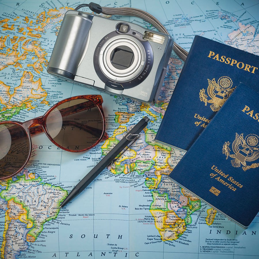 Map with camera, passports, sunglasses and pen laying on it.