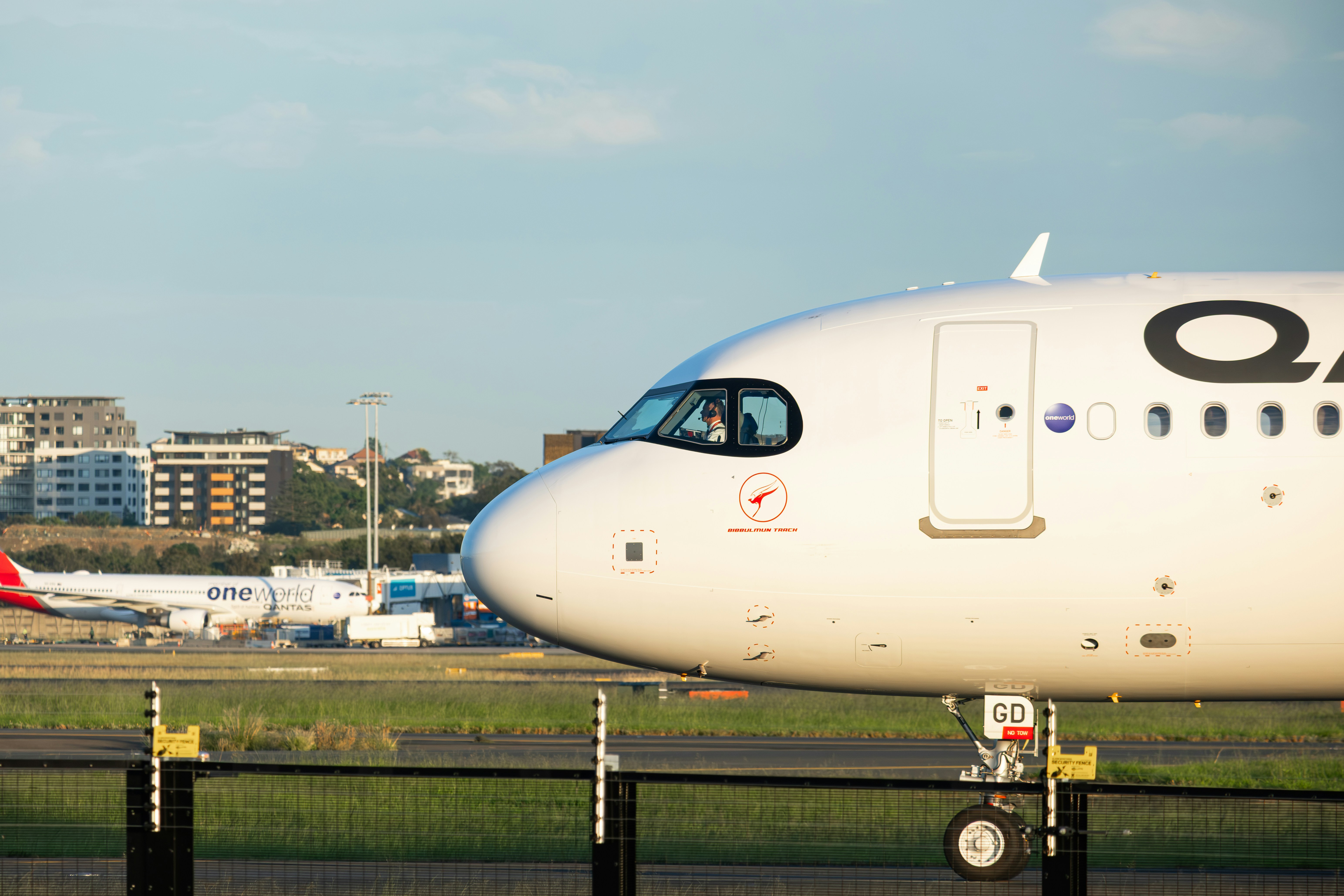 A white airplane with qantas logo on tarmac.