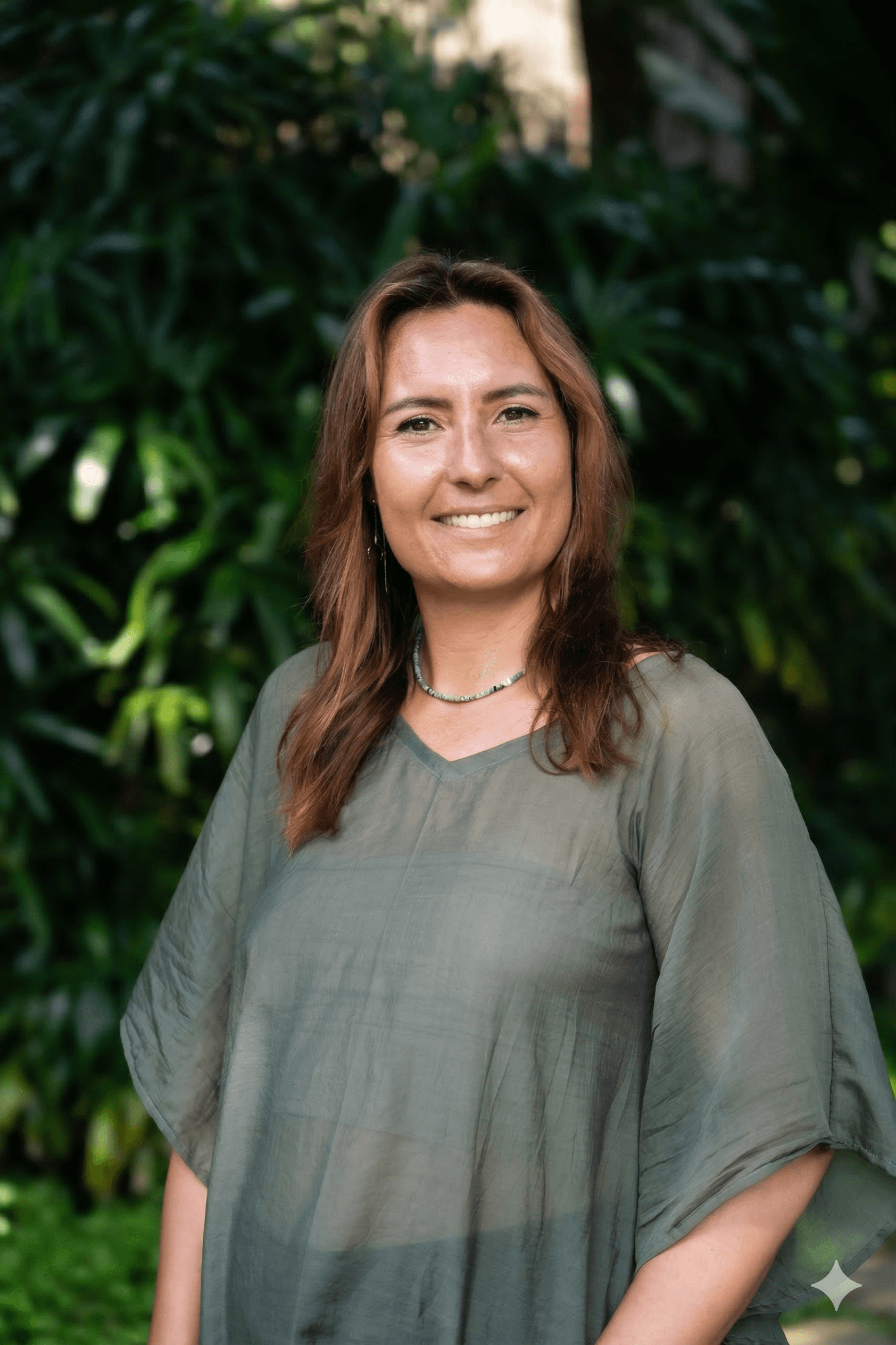 A woman with long hair sits at a desk in an office, working on a laptop with a water bottle nearby.