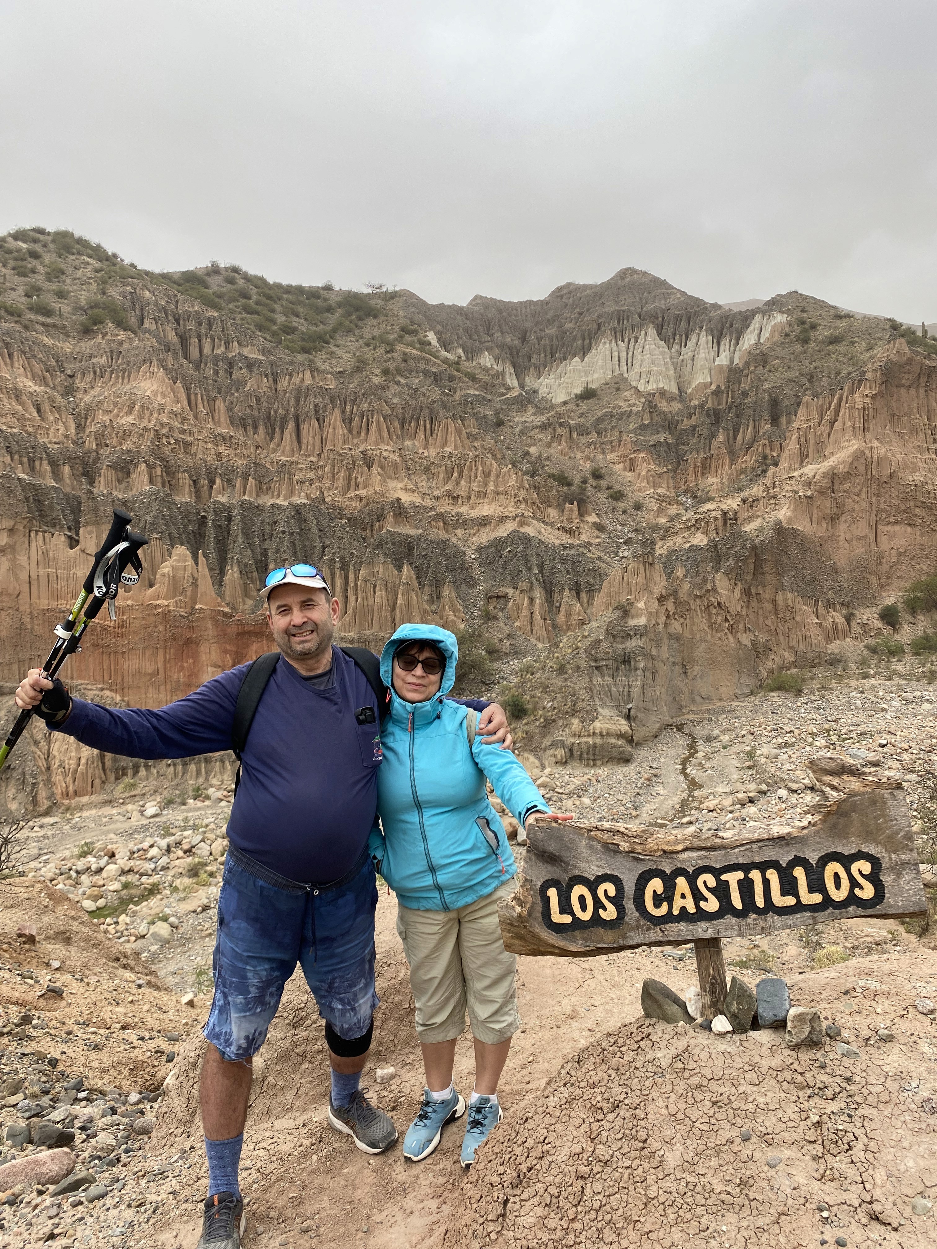 Mujer sentada sobre un tronco frente a una cascada doble en un bosque frondoso de Argentina.
