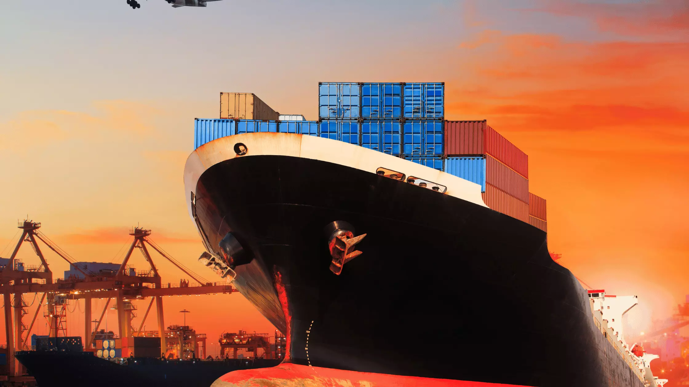 A man stands while two people sit at a table in an office setting, smiling and engaged in conversation. The mood is friendly and collaborative.