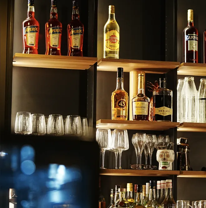 Gemütliche Bar mit Flaschen im Hintergrund, die schön beleuchtet sind.