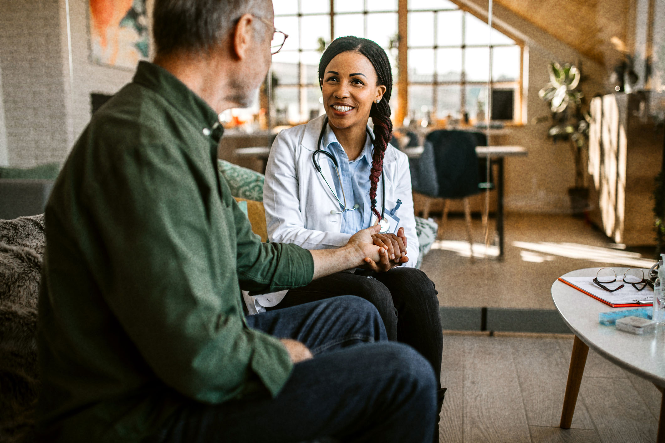 A doctor sitting with a patient on a sofa.