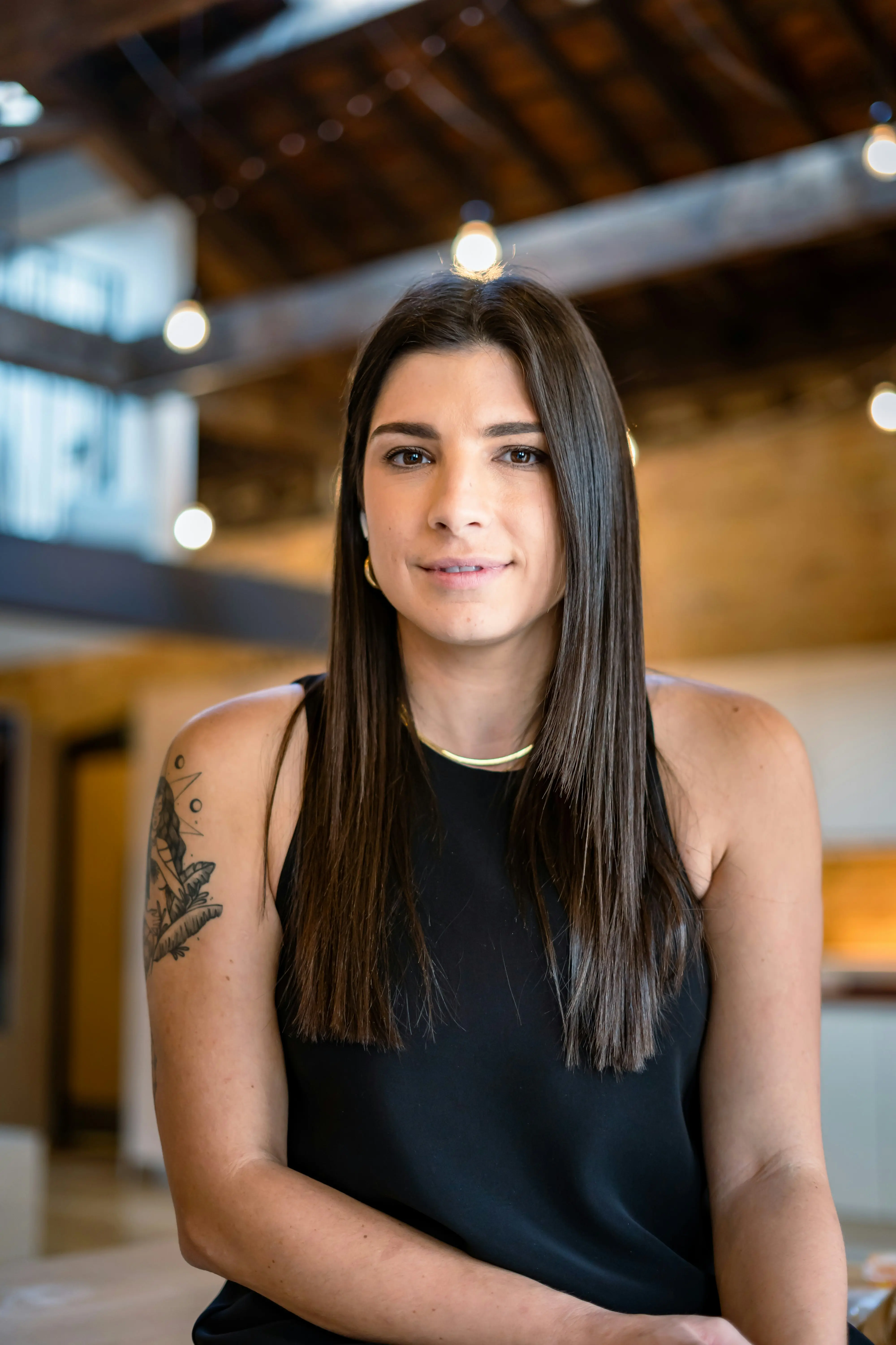 Young woman with a tatto on her right shoulder looking into camera.