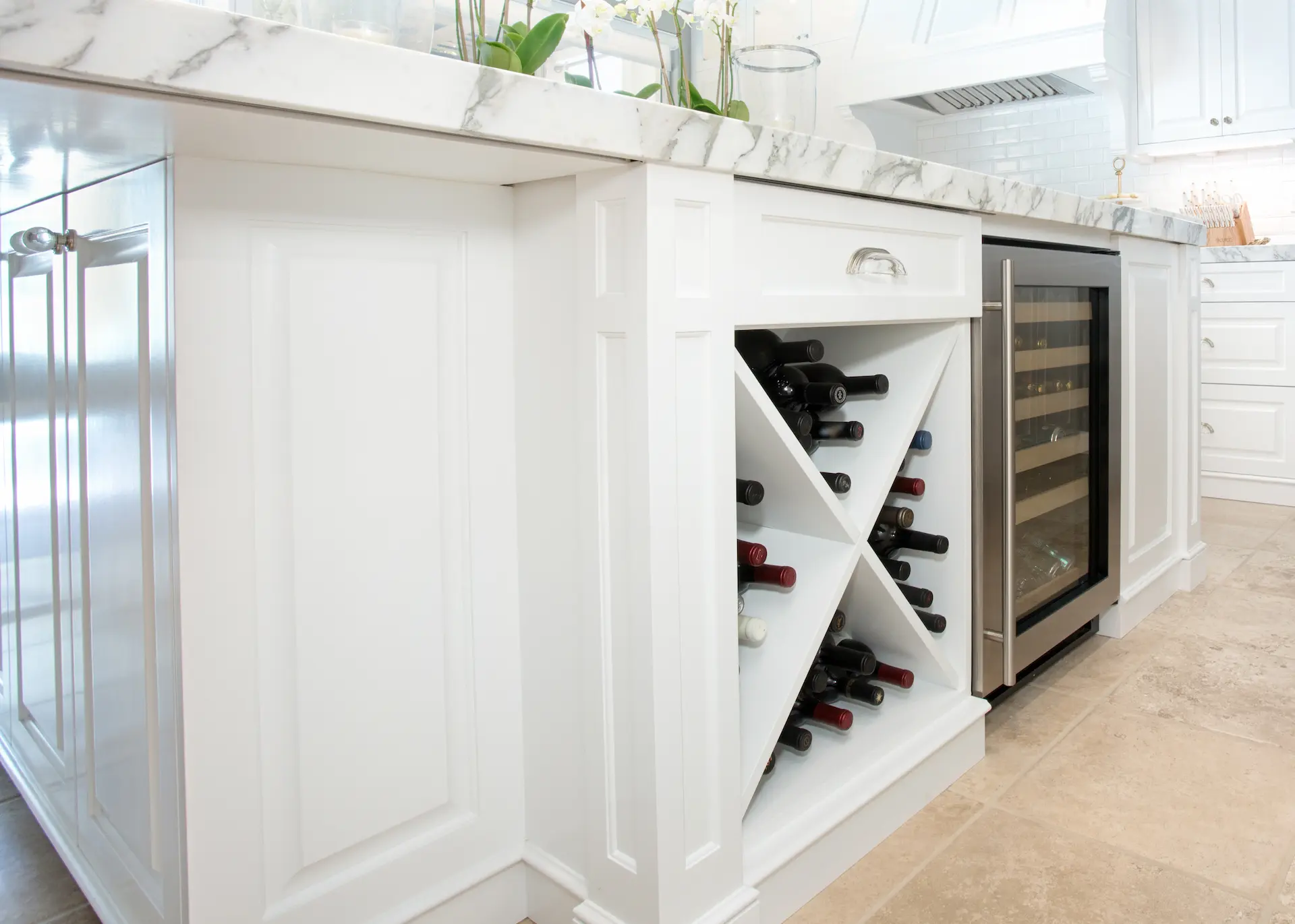 'Newport Beach Remodel' white kitchen island with built-in wine rack and cooler, under marble countertop.